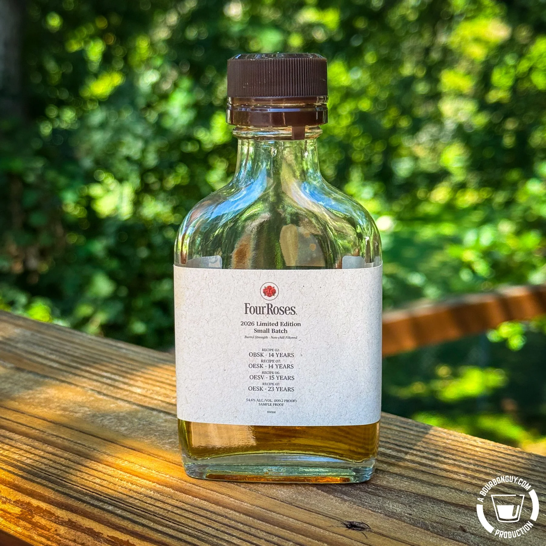 IMAGE: A sample bottle of Four Roses 2026 Limited Edition Small Batch bourbon sits on a wooden deck railing against a softly blurred green background.