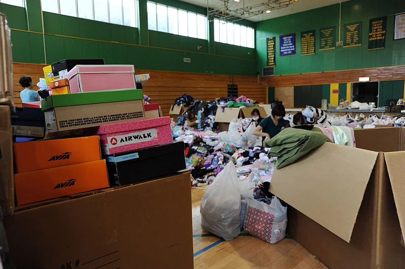 800px-US_Navy_110624-N-ZZ999-070_Stacks_of_shoeboxes_await_sorting_as_Misawa_Air_Base_personnel_organize_materials_donated_to_Japan_by_listeners_of_the_S.jpg