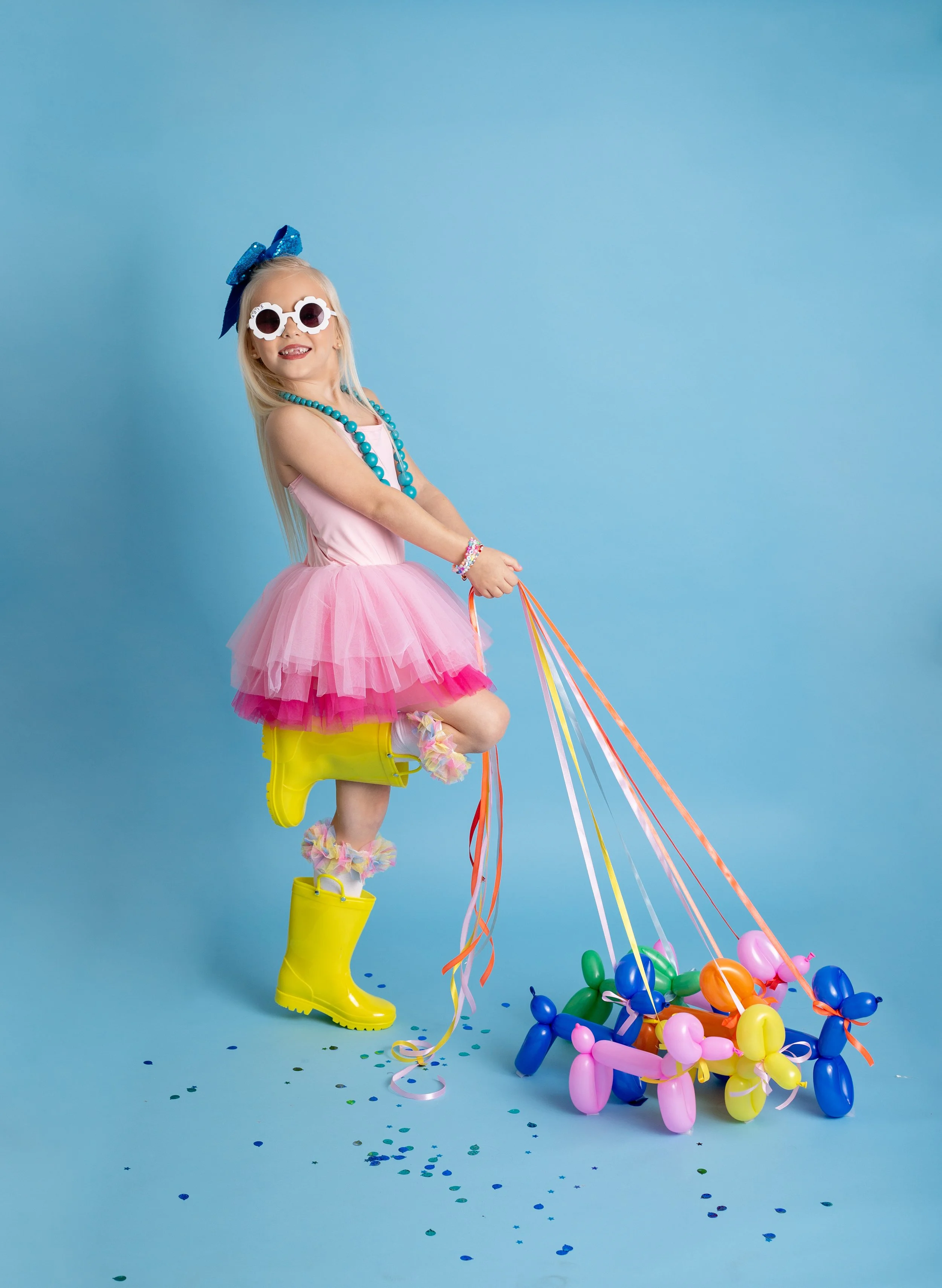 Smiling girl holding a colorful balloon dog during a bright birthday photo session in Gilbert, Arizona.