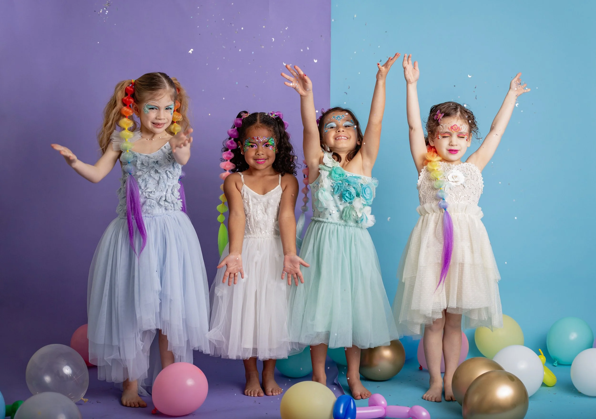 young girls with colorful braided hair extensions and vibrant animal face paint sit together during a studio branding session for an East Valley Arizona face painter, photographed by a Gilbert Arizona child photographer.