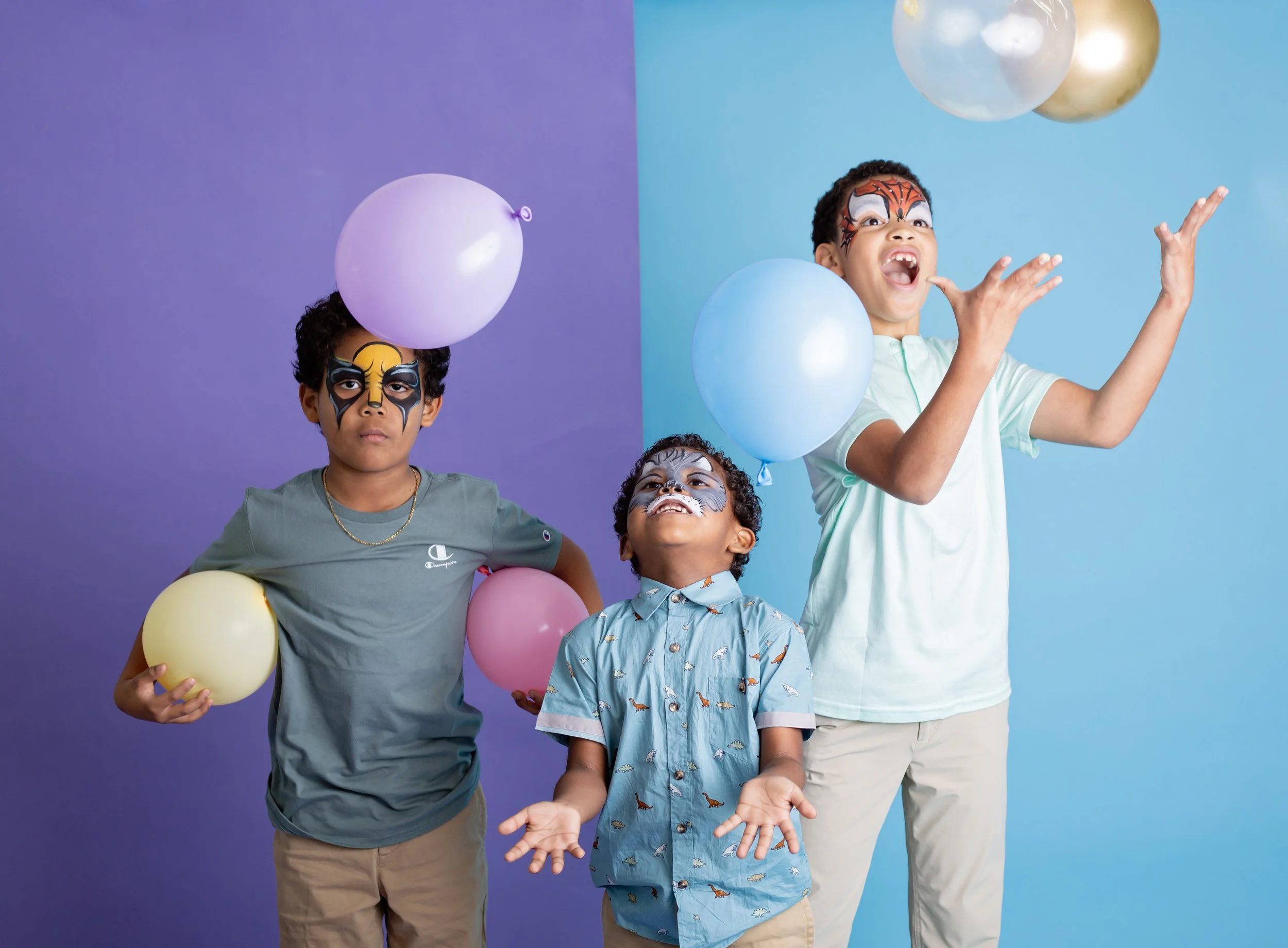 young girls with colorful braided hair extensions and vibrant animal face paint sit together during a studio branding session for an East Valley Arizona face painter, photographed by a Gilbert Arizona child photographer.