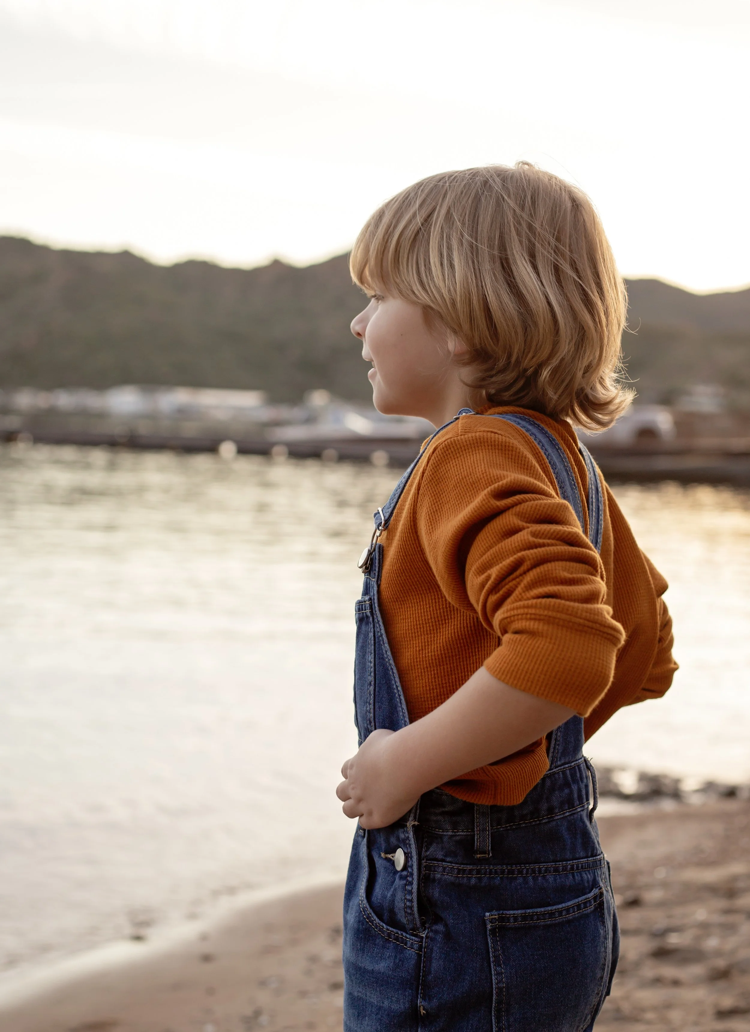Child sitting on a dock holding a fishing pole and watching the water at sunset in Arizona, photographed by a Gilbert family photographer