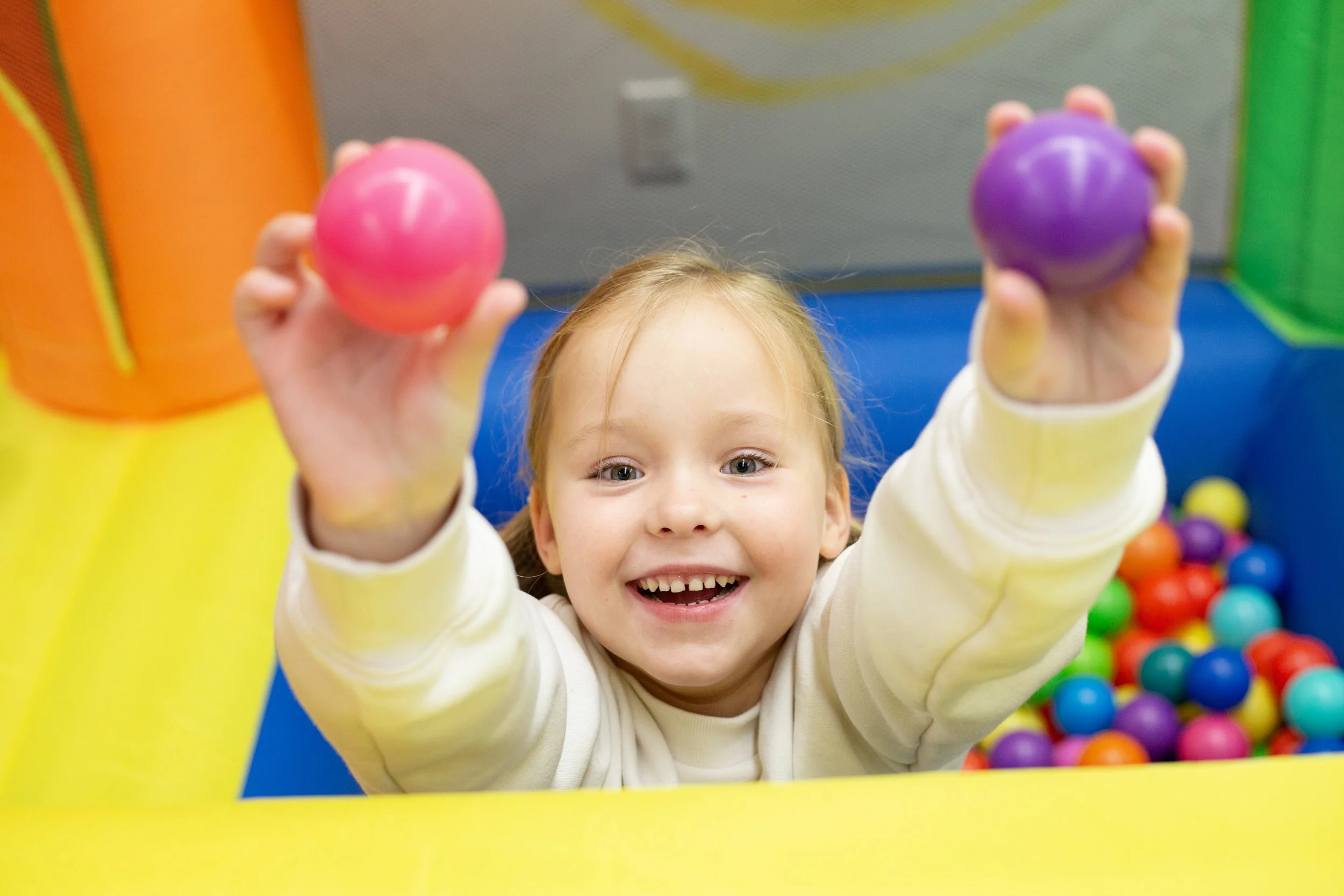 A child plays in a ball pit inside this mesa arizona playspace and community space for parents