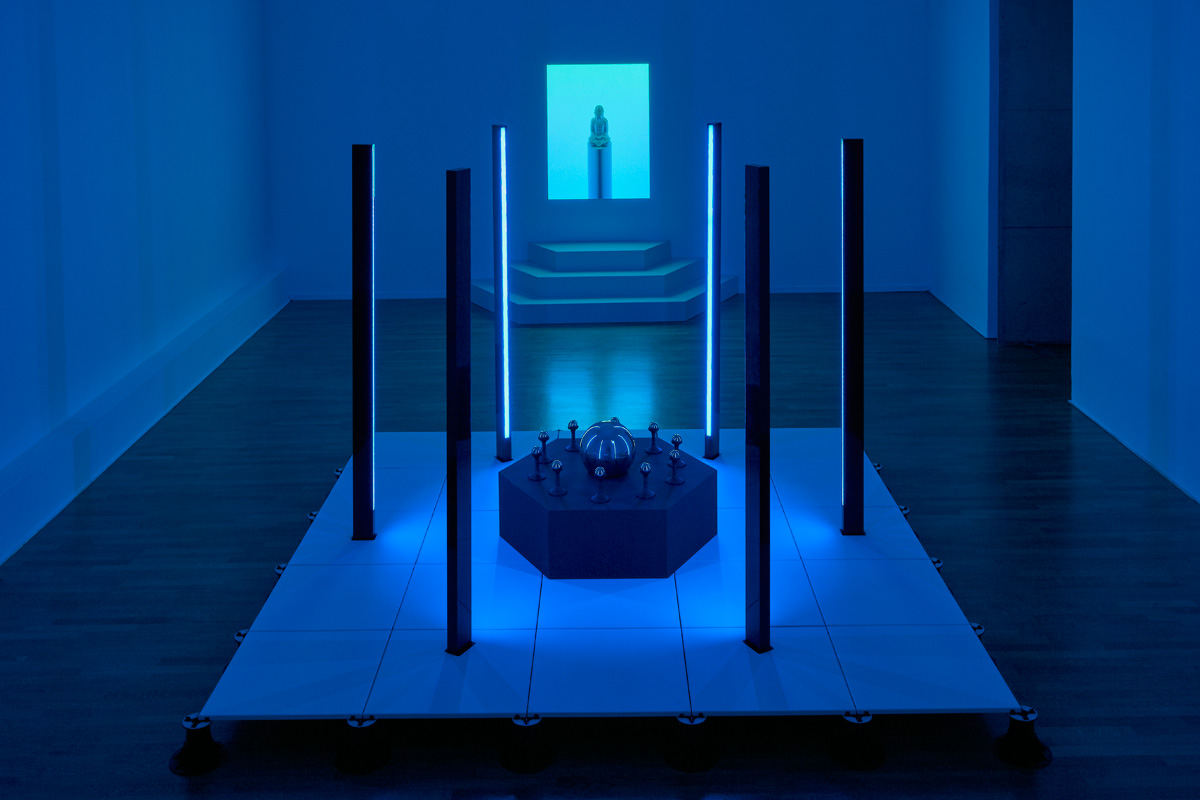 //// ROOM 01 - A precision CNC platform on pedestals, with custom fabricated aluminium LED light columns, and CNC routed table with Jesmonite holders and spheres. The rear artwork is an an illusionary light installation that appears as a projection, consisting of a 3d printed an Jesmonite cast Buddha statue installed into a temporary gallery wall and backlit with LEDs.