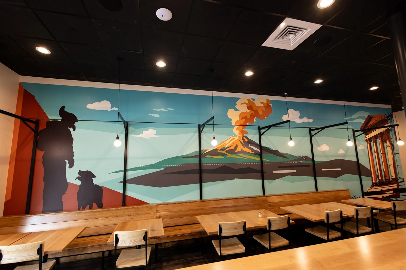 Custom mural by Charlotte mural artist Kyle Mosher inside the new Inizio Pizza Cotswold restaurant featuring Mount Vesuvius, Pulcinella, Italian-inspired illustration, and a minimal vintage postcard aesthetic.
