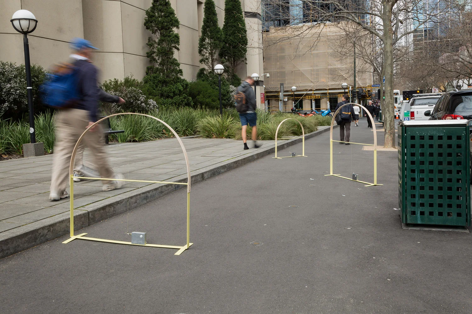 Beth Arnold, Keep in Time , 2016. Test Sites commissioned project, City of Melbourne, timber, steel, kinetic element, string, dimensions variable. Date: 5th September 2016. Location: Footpath outside 288 Exhibition Street. All photos by Christo Crocker. "Through this project I am interested in creating an artwork that sits playfully amongst the hustle and bustle of the city. 'Keep in time' is a performative sculpture activated through movement. Comprising of three structures, each with a tensioned arch, the sculptures start to bob up and down whenever movement is detected, such as a pedestrian walking by or a car and tram passing. Similar to the constant ‘bobbing’ style of early Walt Disney cartoons, the sculptures perform with a wobble and visual rhythm. This movement is achieved by the timber arch moving in and out of distortion. In this sense the sculpture is active and responsive to it's environment. I aim to reflect the city’s humming rhythm and flow in a playful and humorous way." - Beth Arnold 2016