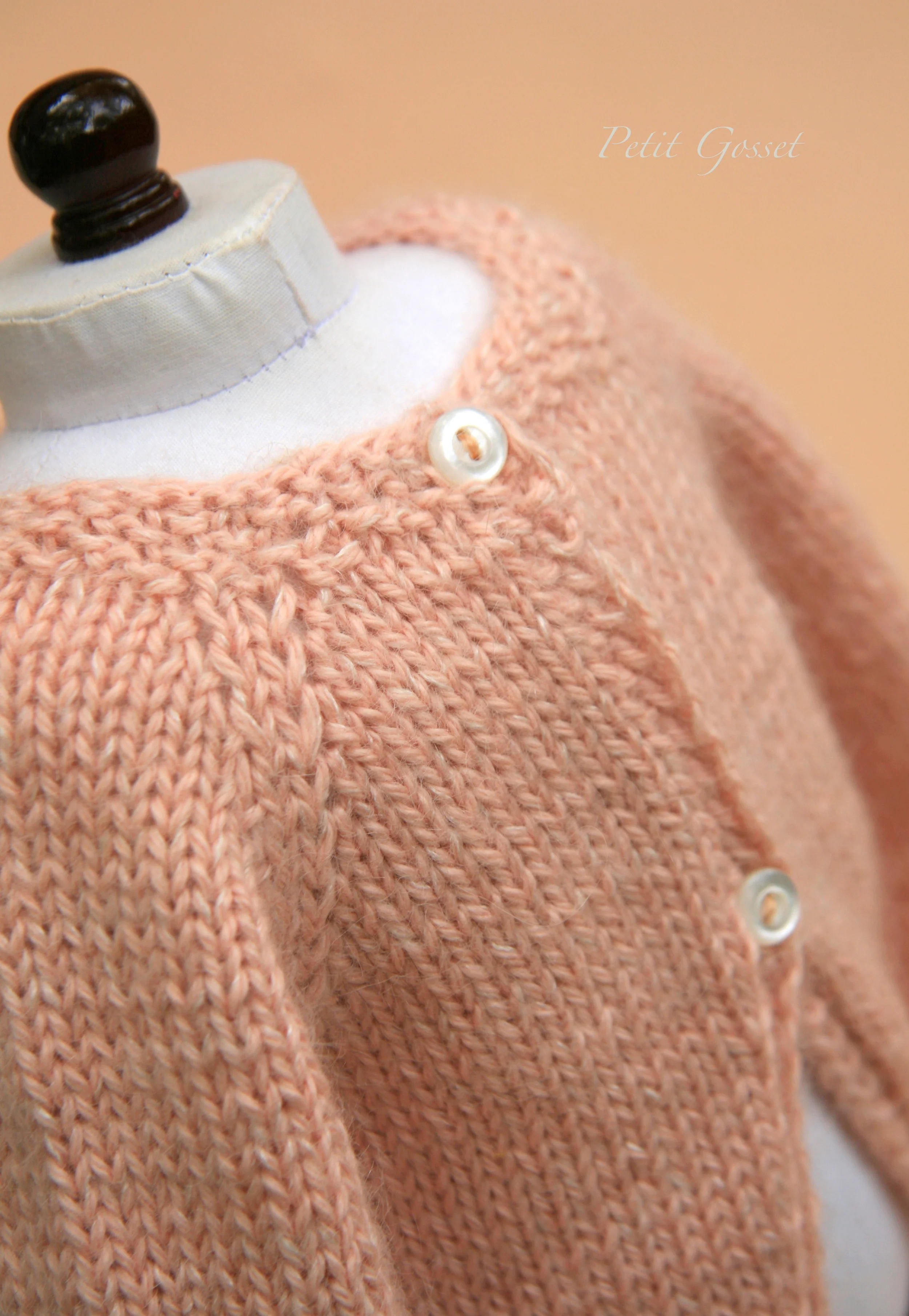 The sweater opens in the back with two little purl buttons