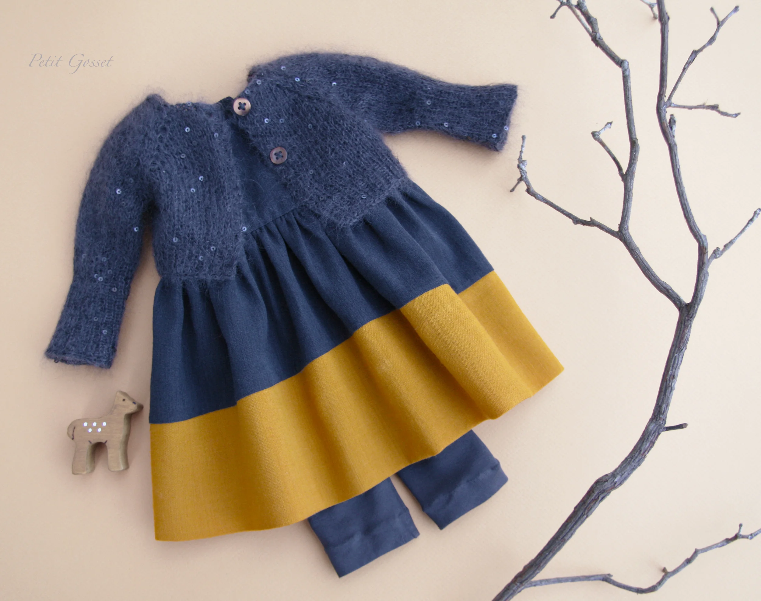 A exquisite wool sleeveless dress, cotton leggings, and a hand-knitted mohair/silk with sequins cardigan. A cute little fawn will come with the set.