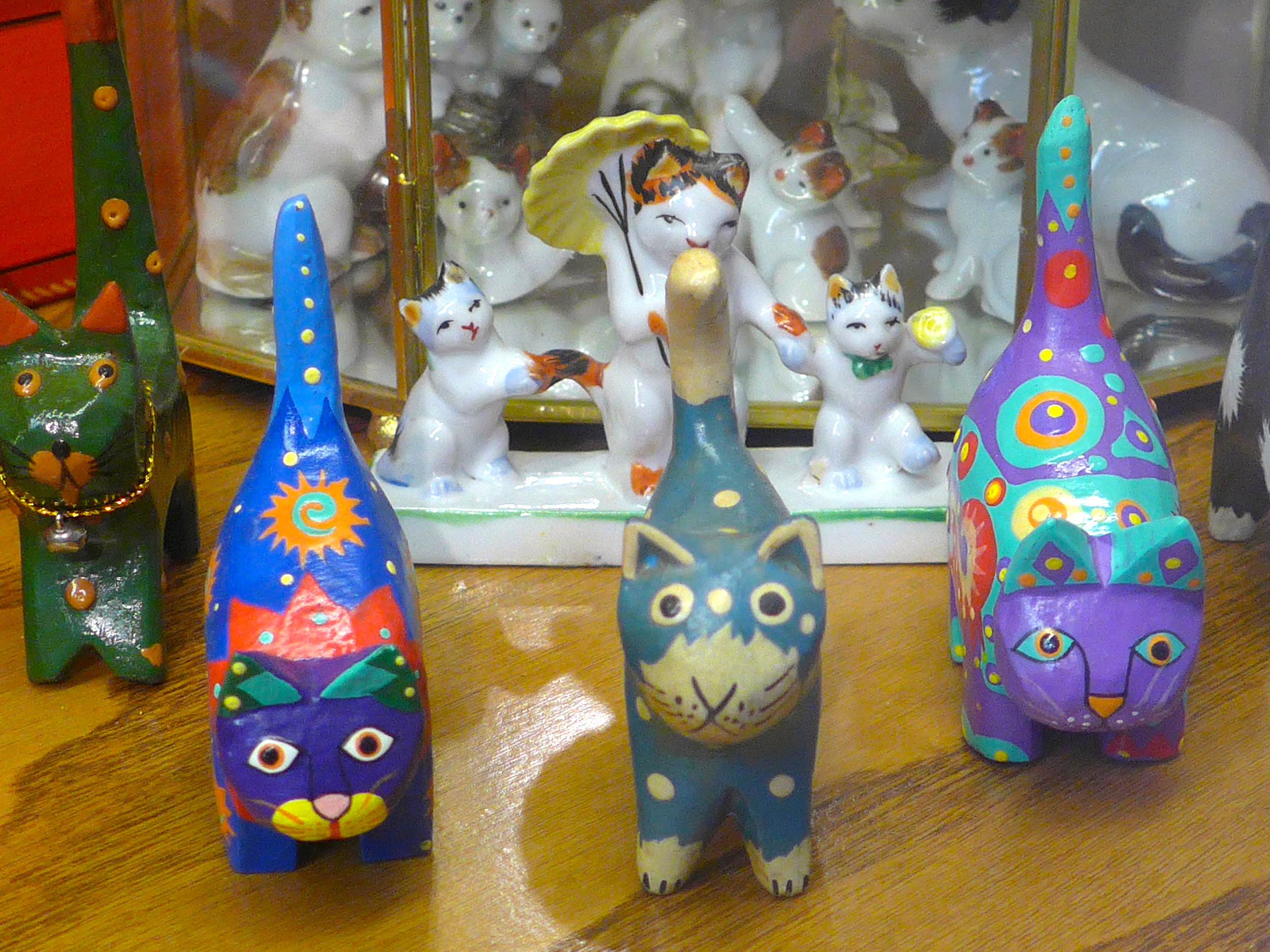 Polychrome carved wooden cats with porcelain mother and kittens behind