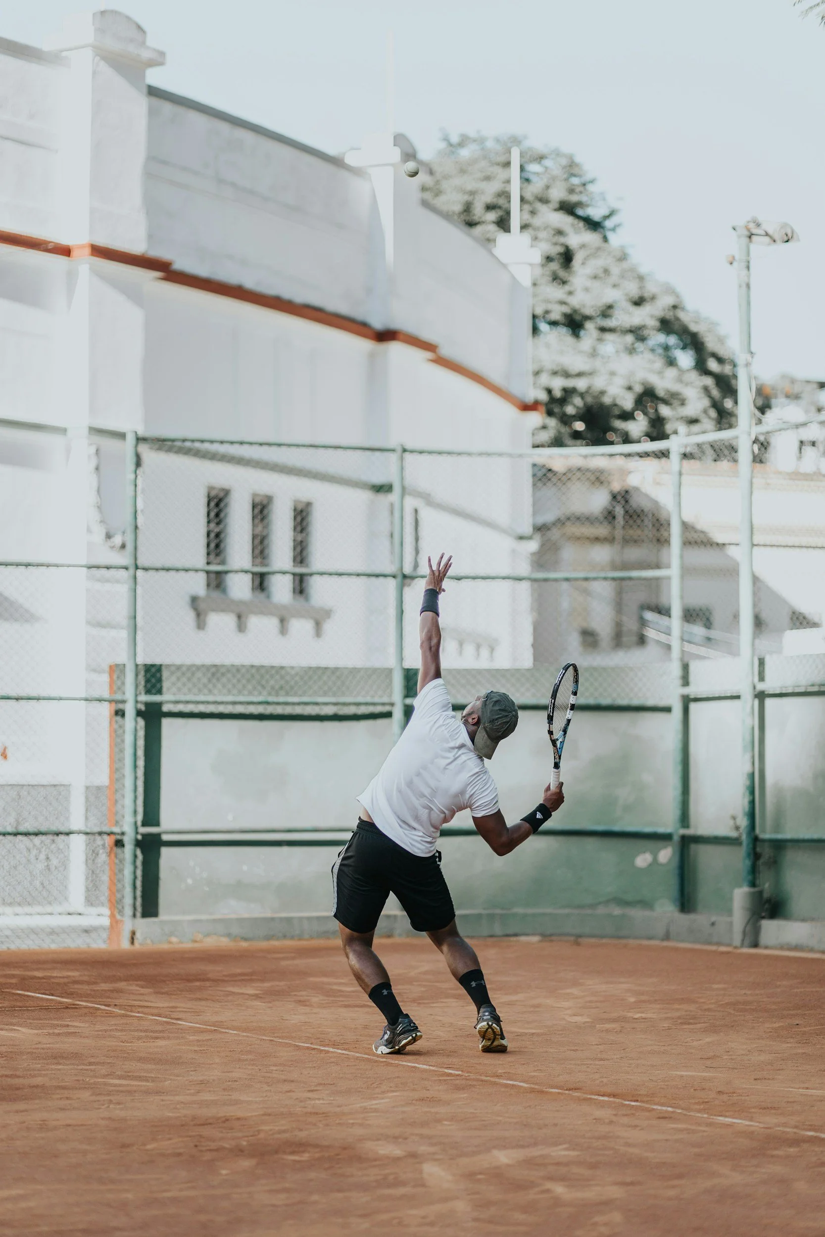 A tennis player throwing the ball up for a serve on a clay court