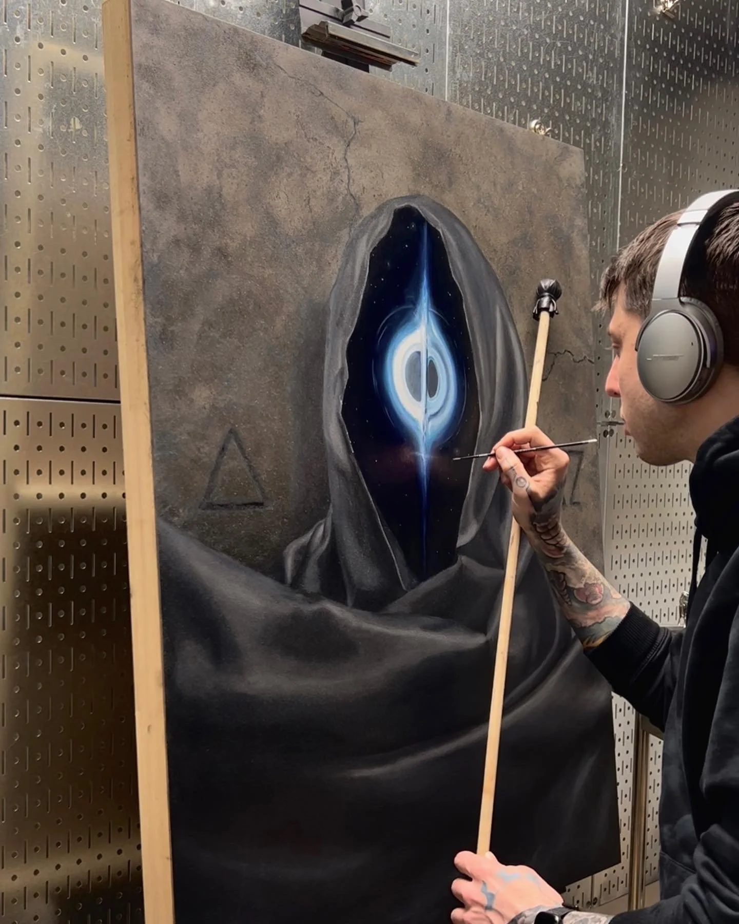 Andrew Matela painting the hooded black hole figure in his studio, oil painting in progress