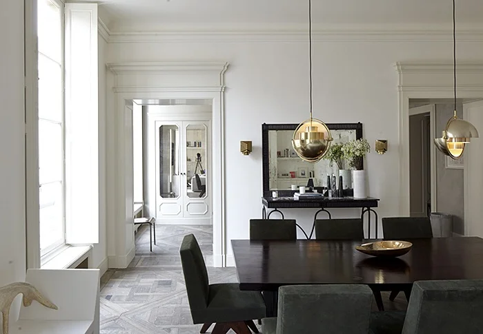 White and grey dinning room with contrasting sharp and dark dinning able and gold pendants