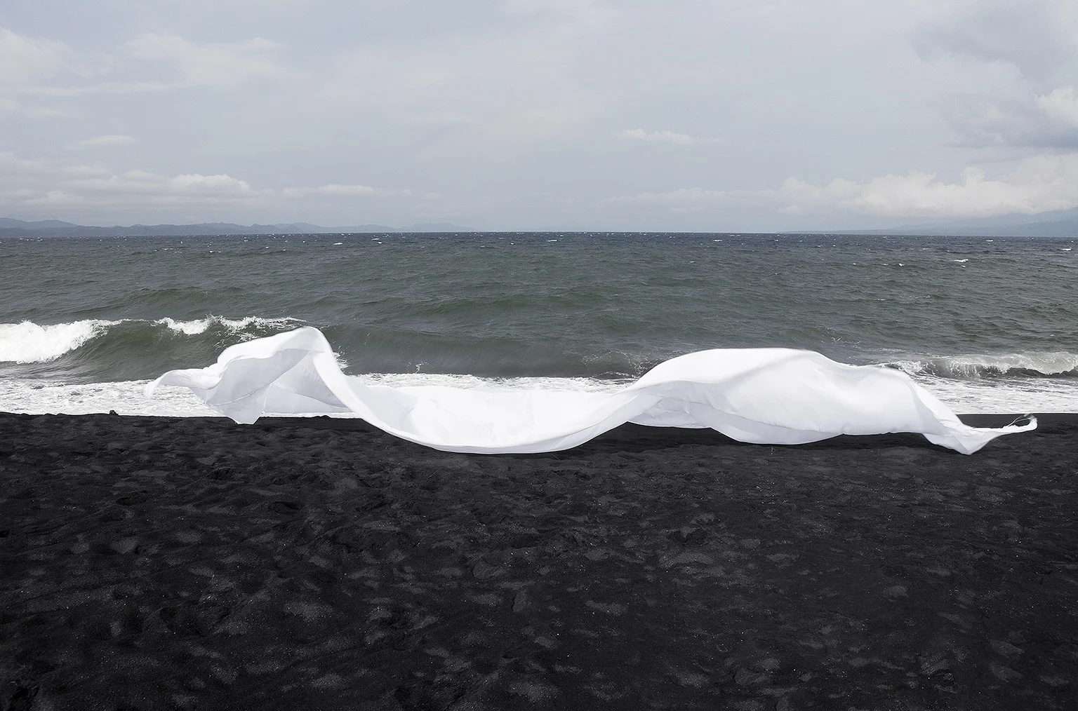 Contrasting poised sheet movement over dark and detailed rocks and rolling waves