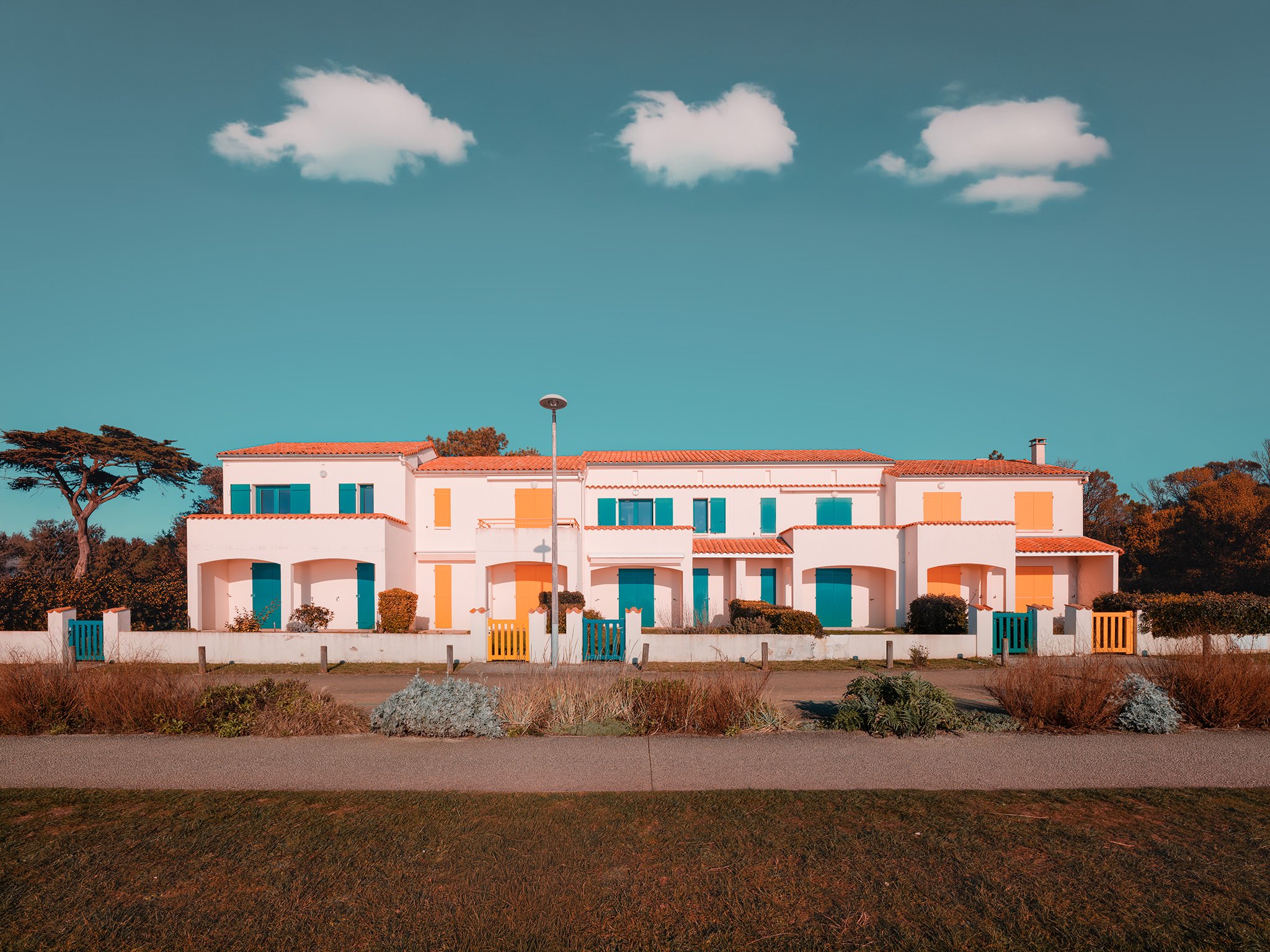Modern white building with black doors and railings, under a clear blue sky.