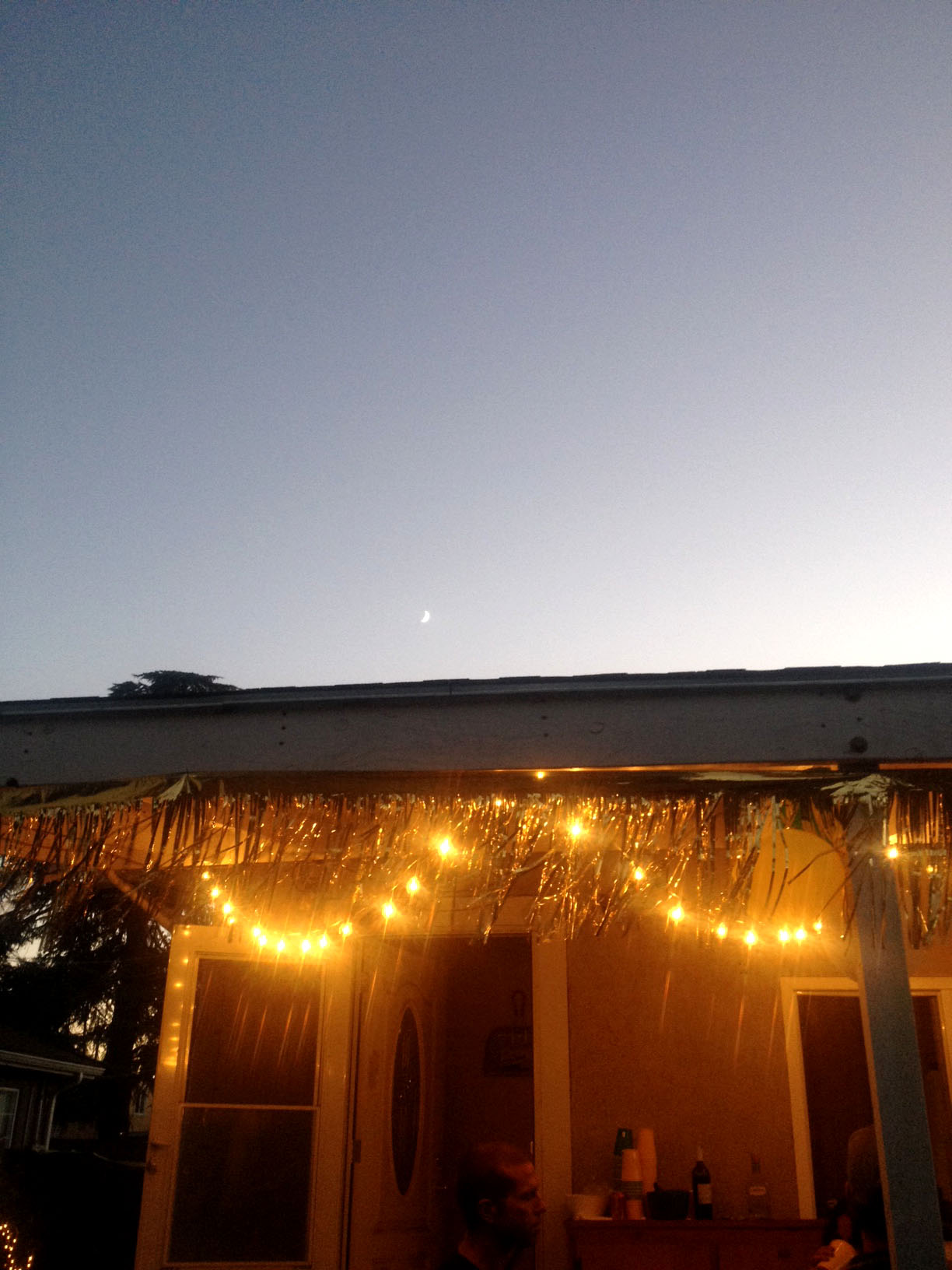 The crescent moon over some gold fringe. 