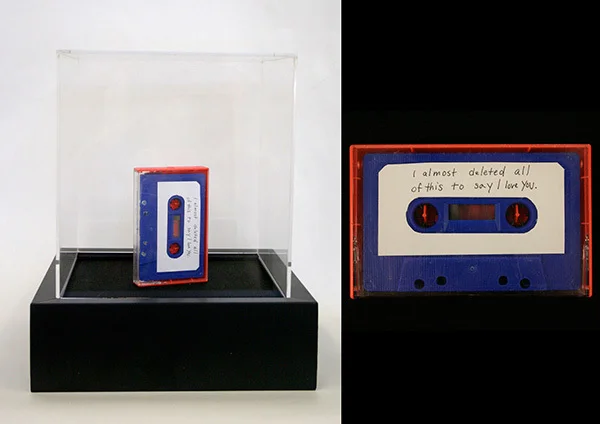   The secret to life is that I miss you.&nbsp; 2010, 10” x 10” x 8” Display box, tape and label stating materials as:    “ Quote from your third to last email, most frequently used lyrics,&nbsp; 32 second sound piece created from top ten words collec