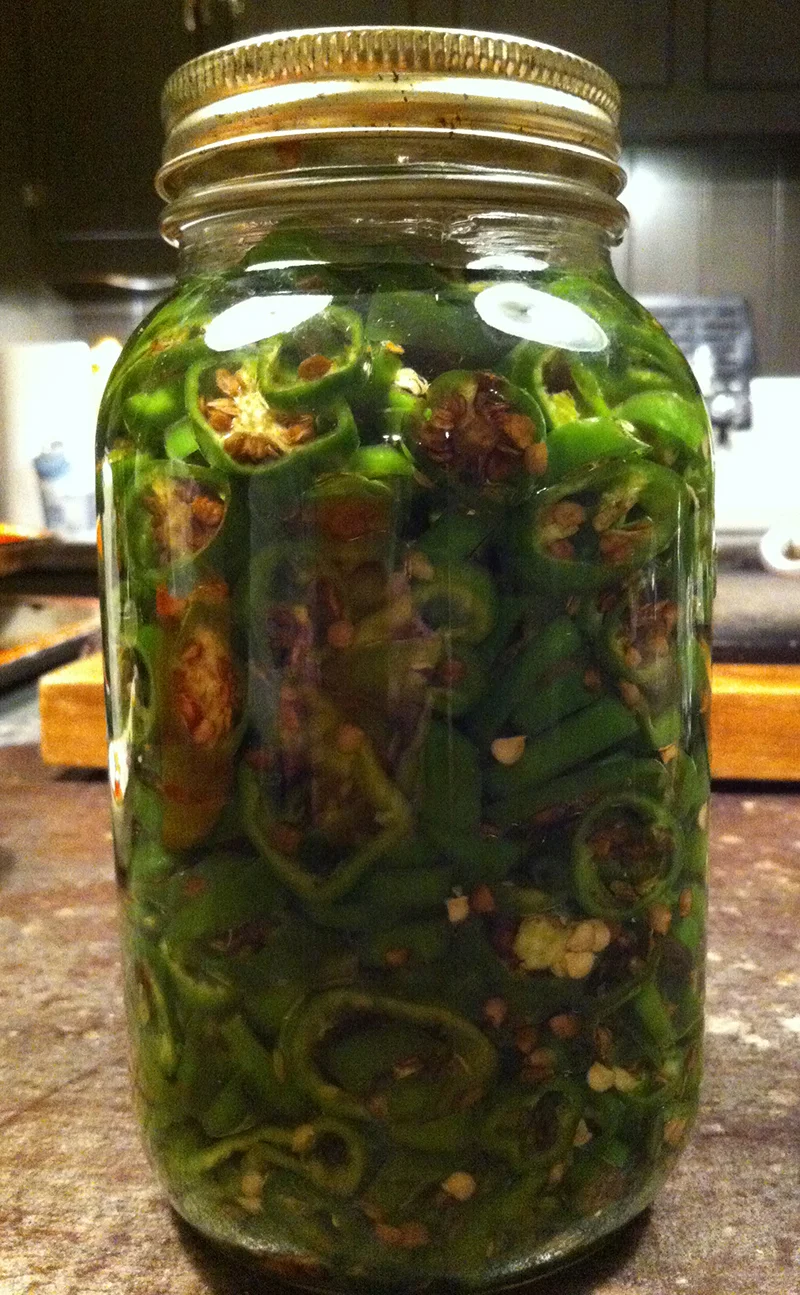 Pack the peppers in mason jars or tupperware and cover completely with canola oil and put them in the fridge. Canola oil works best because it doesn't solidify in the fridge like Olive oil. That's it! Leave them for about a week and then enjoy them on burgers, pizza, pasta, sandwiches...whatever you like. 