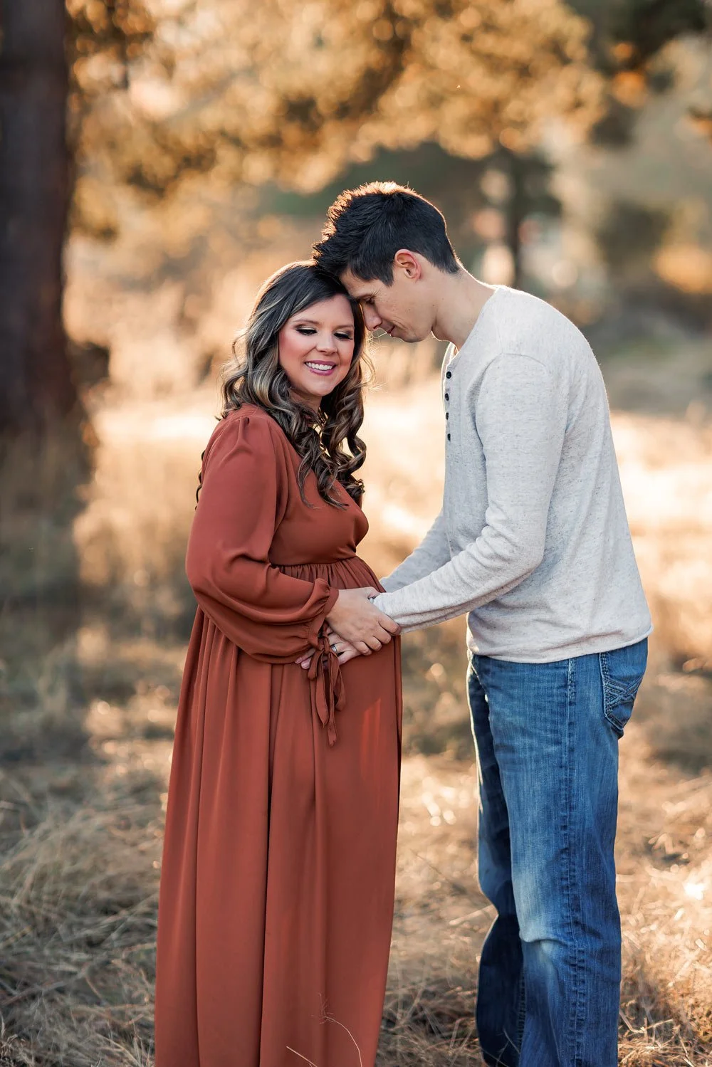 Expecting couple standing together in field holding baby bump during maternity session near portland oregon