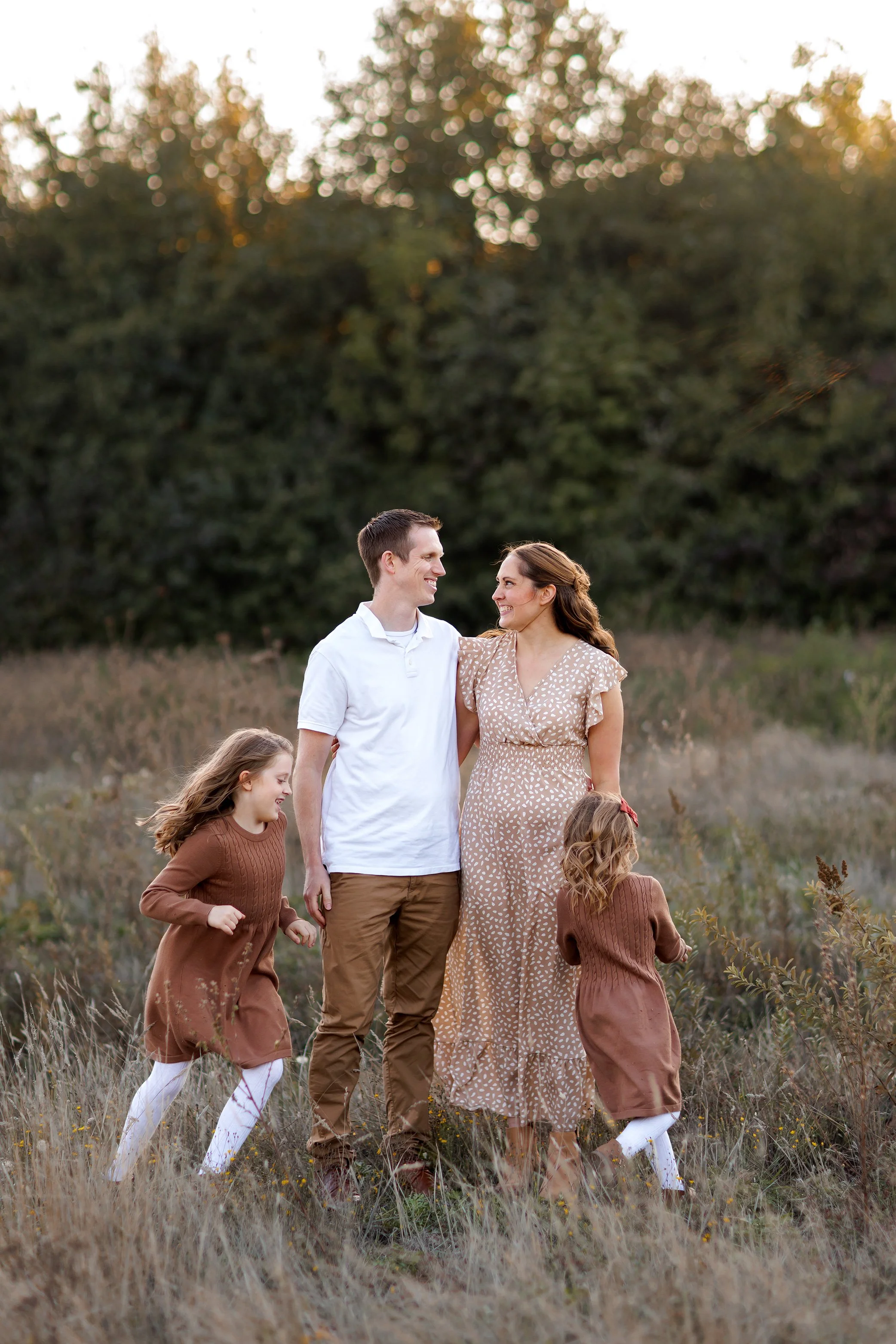 parents smiling at each other while daughters move around them in field