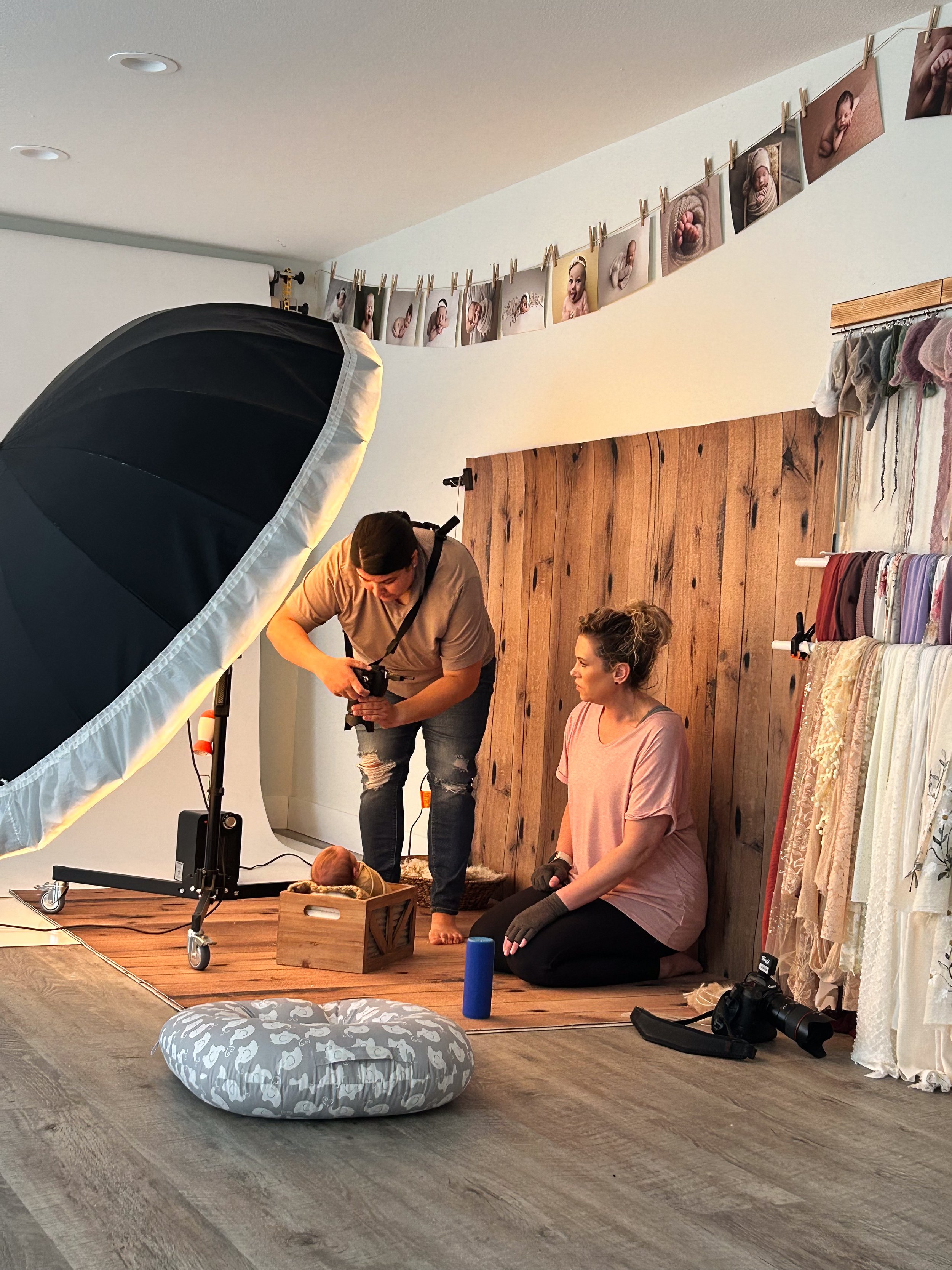 Behind the scenes of newborn photography training showing lighting setup, posing guidance, and hands-on mentoring with a real baby session