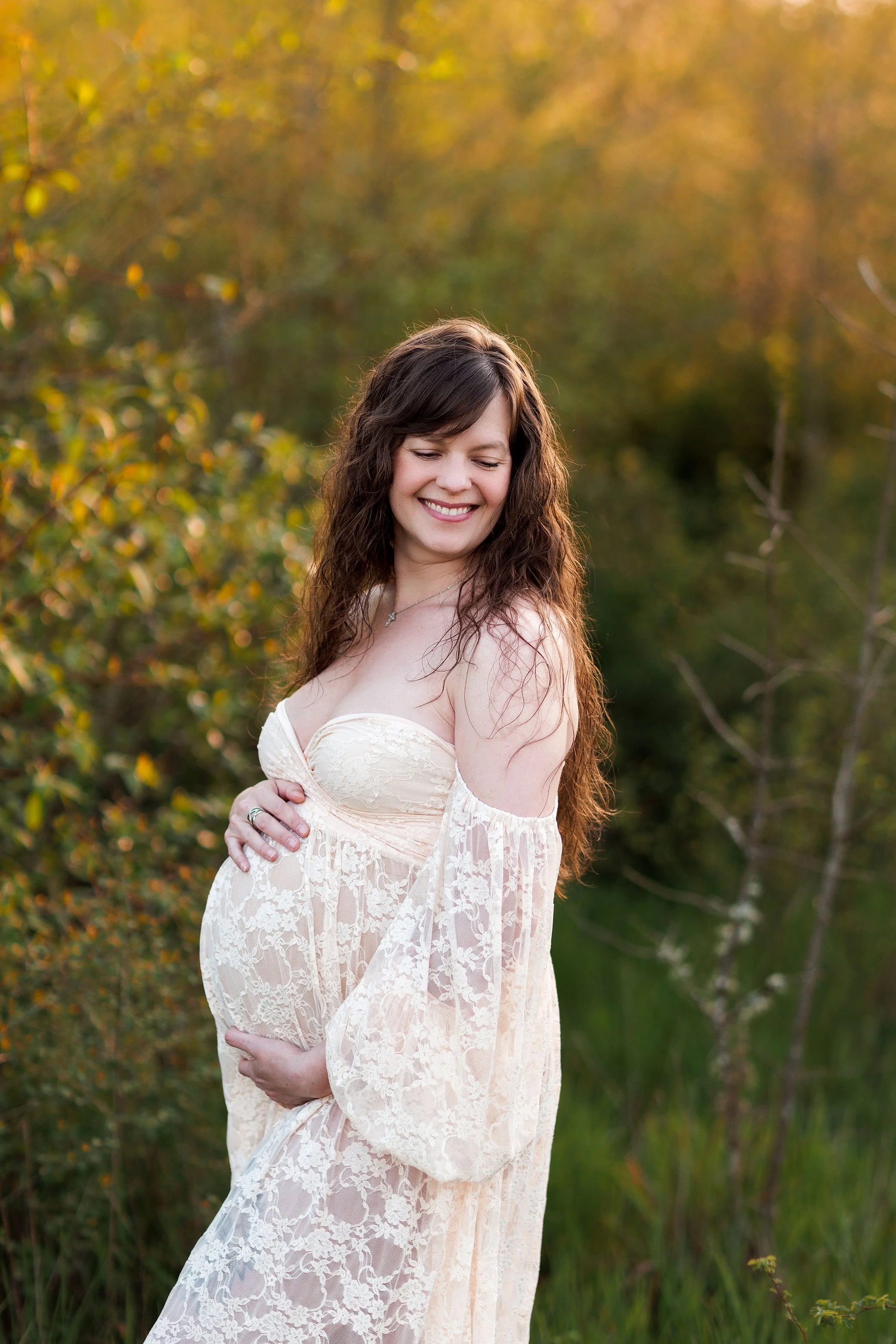 Pregnant mother in lace dress smiling in golden field during outdoor maternity session in Salem Oregon