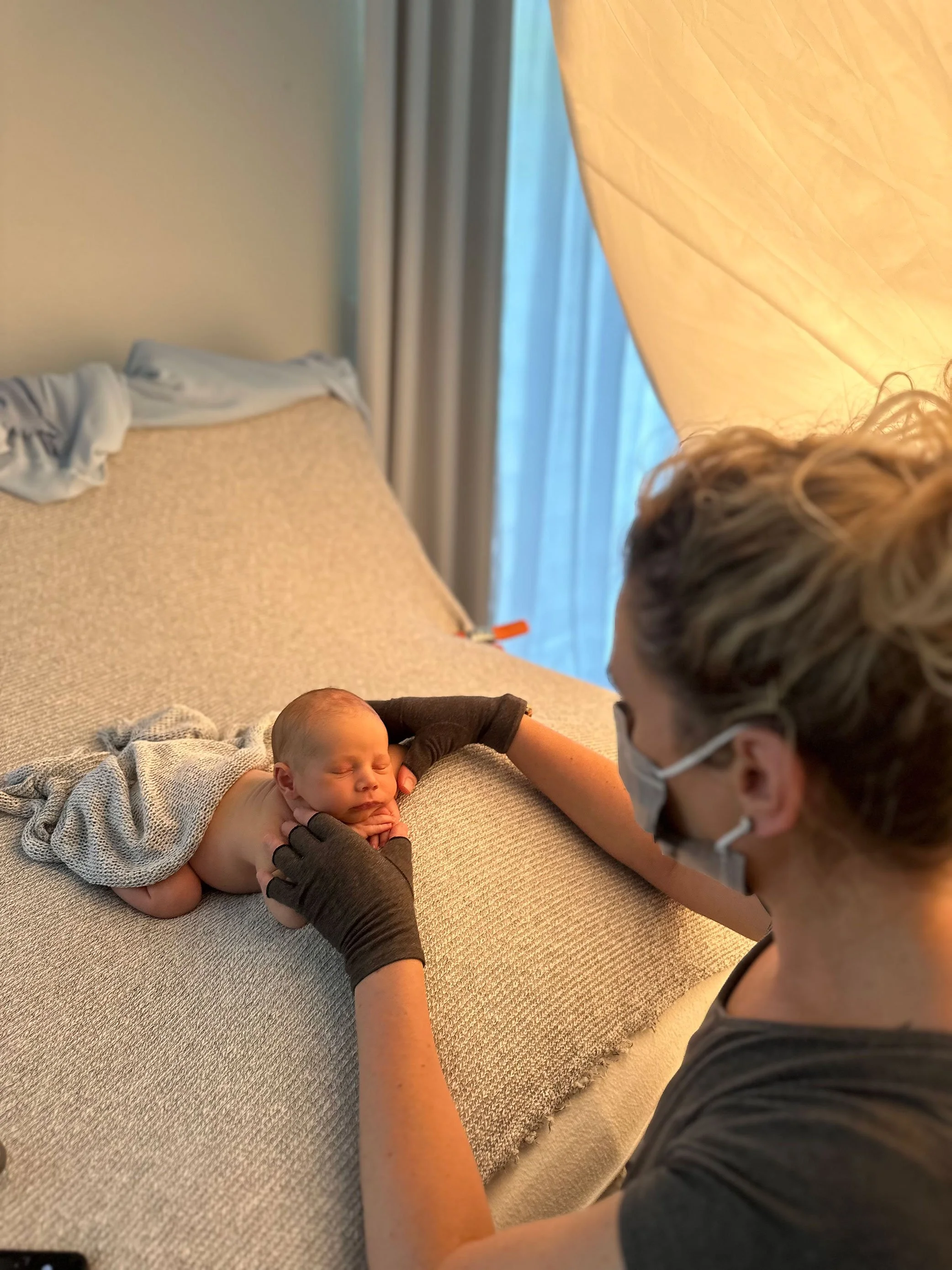 Newborn photographer demonstrating safe posing techniques during one-on-one mentoring session with hands-on guidance