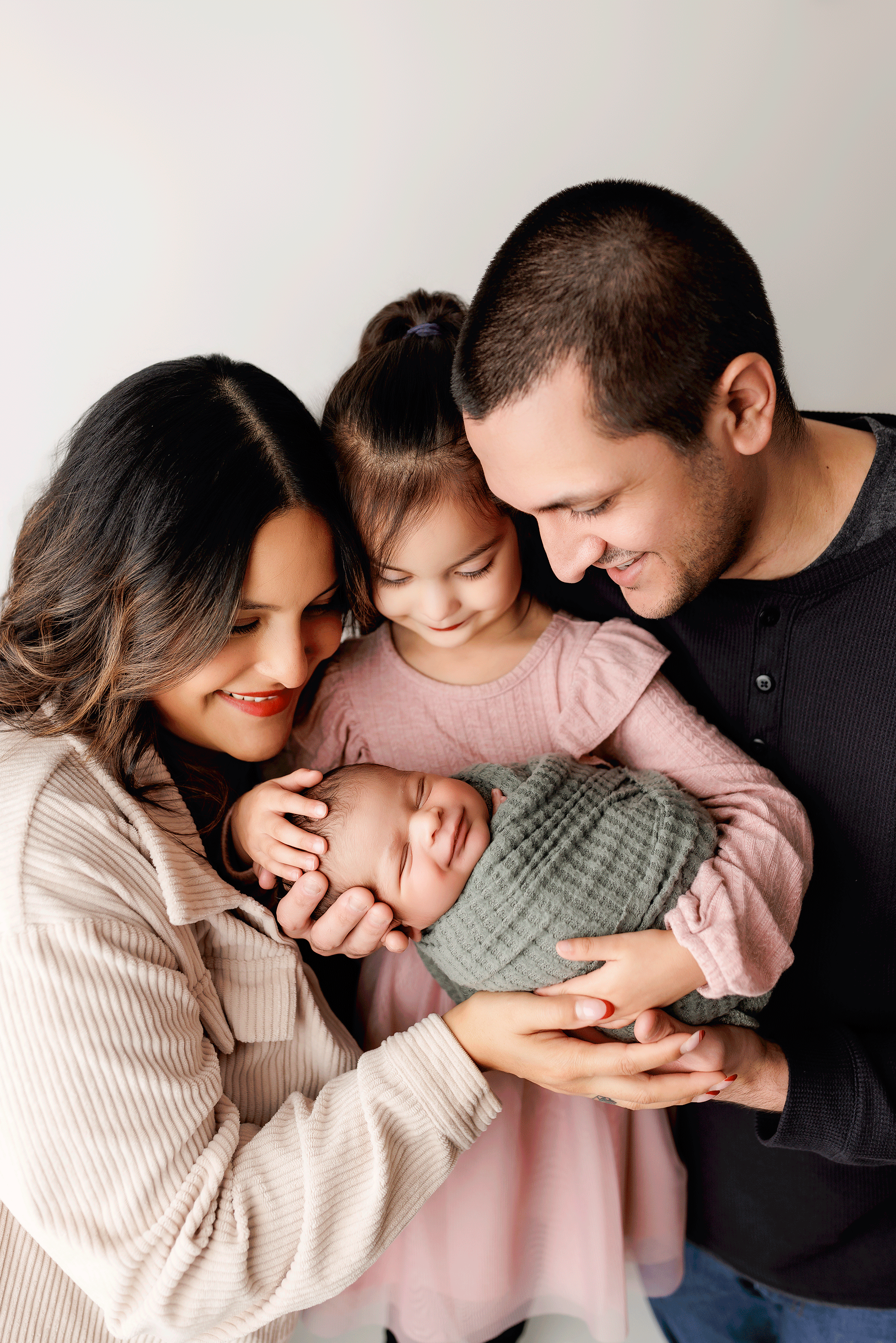 Parents and toddler looking down at their newborn during a professional newborn photography session in Salem, Oregon.