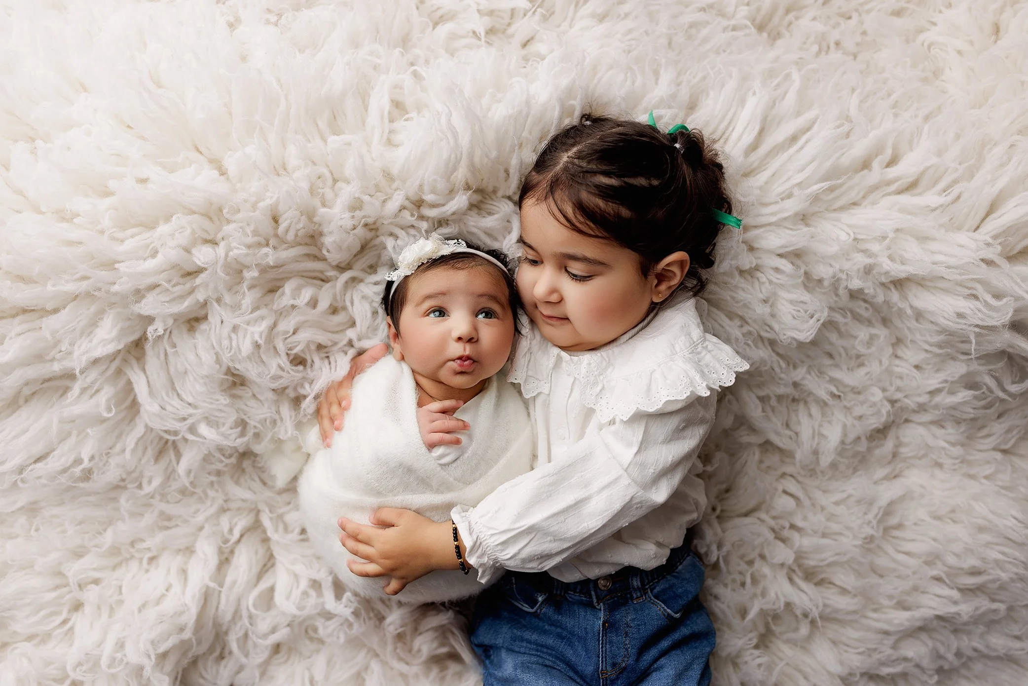 Toddler smiling down at their newborn sibling during a professional newborn photography session in Salem, Oregon.