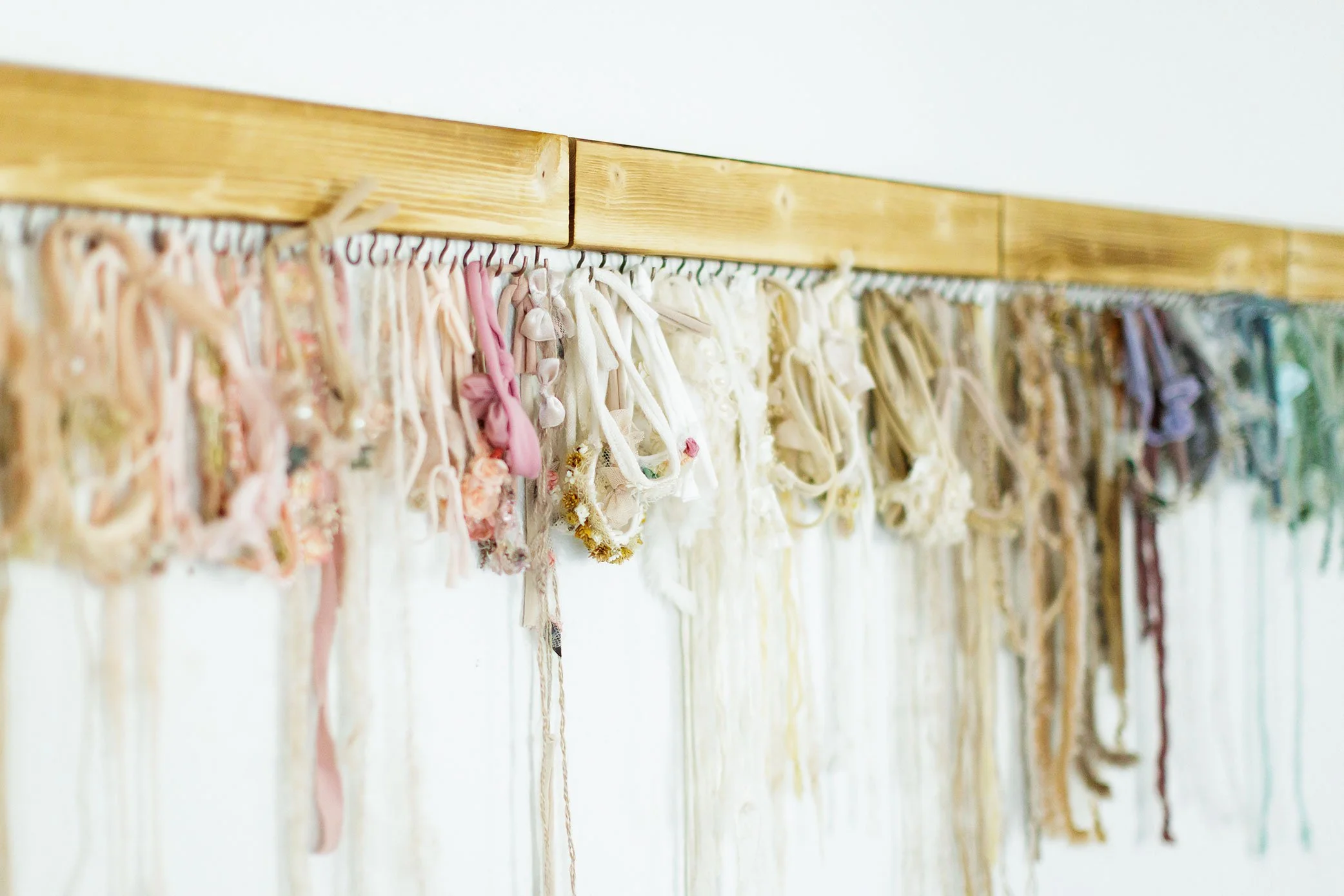Collection of soft neutral newborn headbands and styling pieces hanging in photography studio