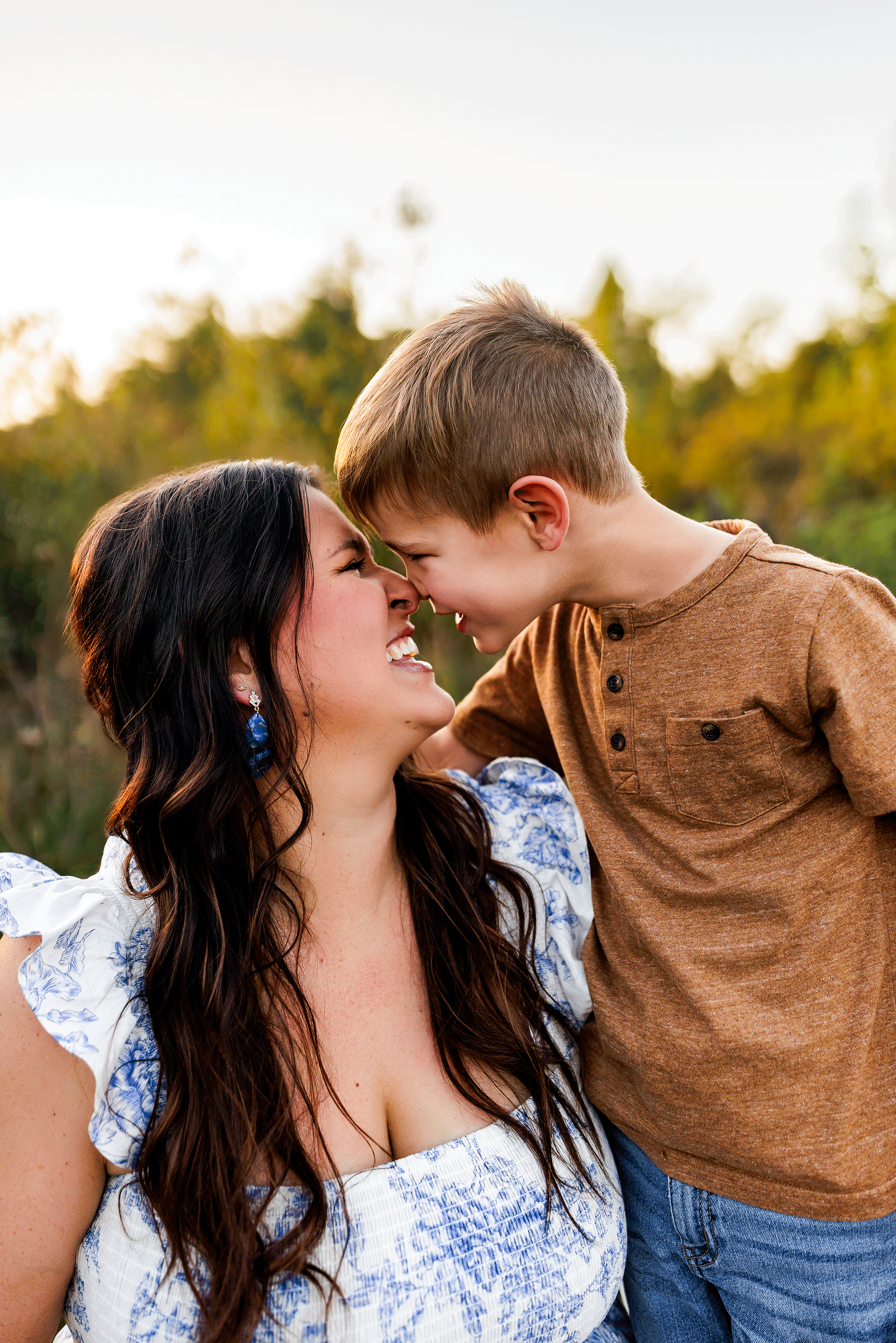 Mother and young son touching noses and smiling during golden hour outdoor family photography session in Salem Oregon