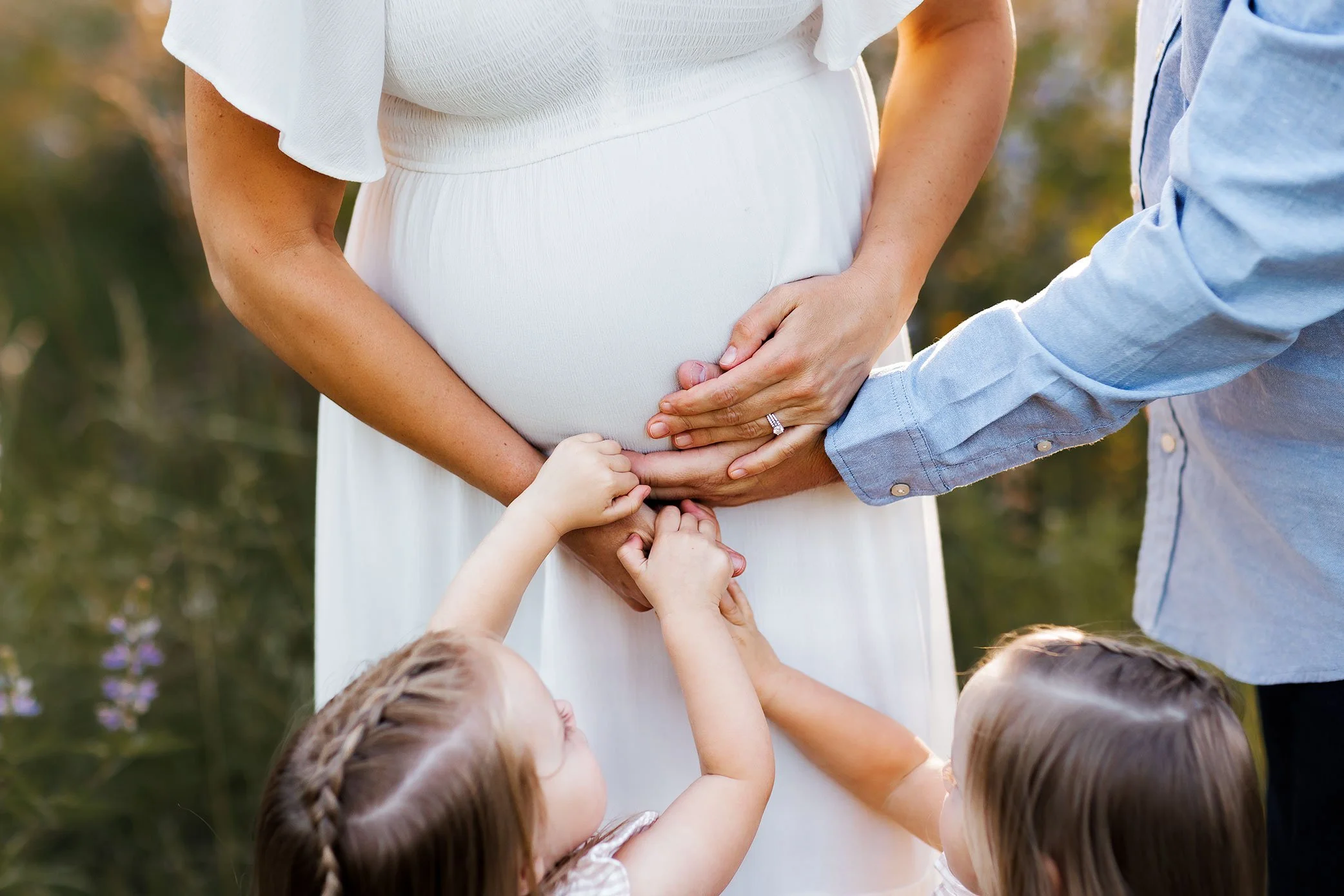 Parents and children placing hands on pregnant belly during outdoor family maternity session in Salem Oregon