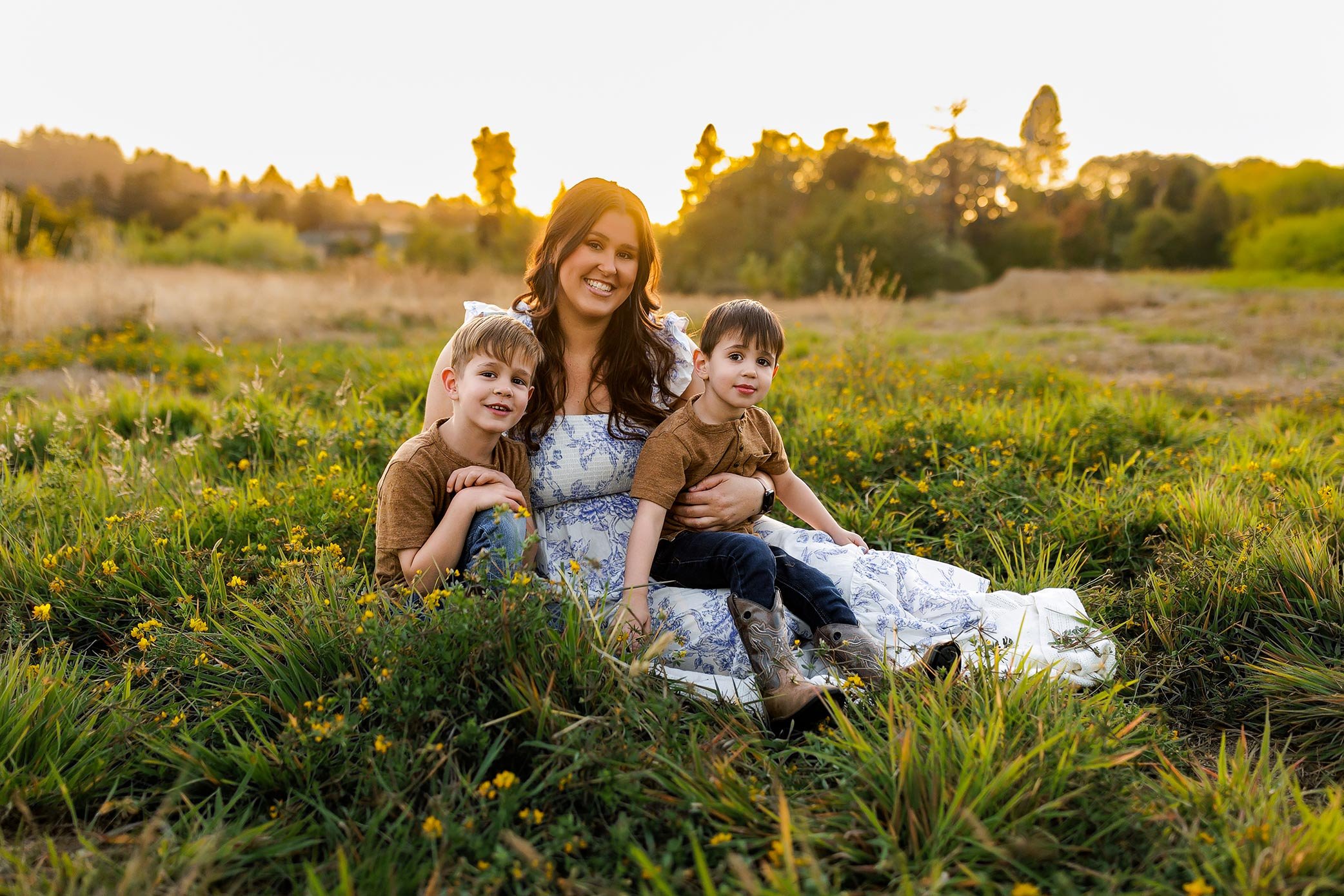 A woman hugging a smiling girl in a field, both appearing happy and relaxed.