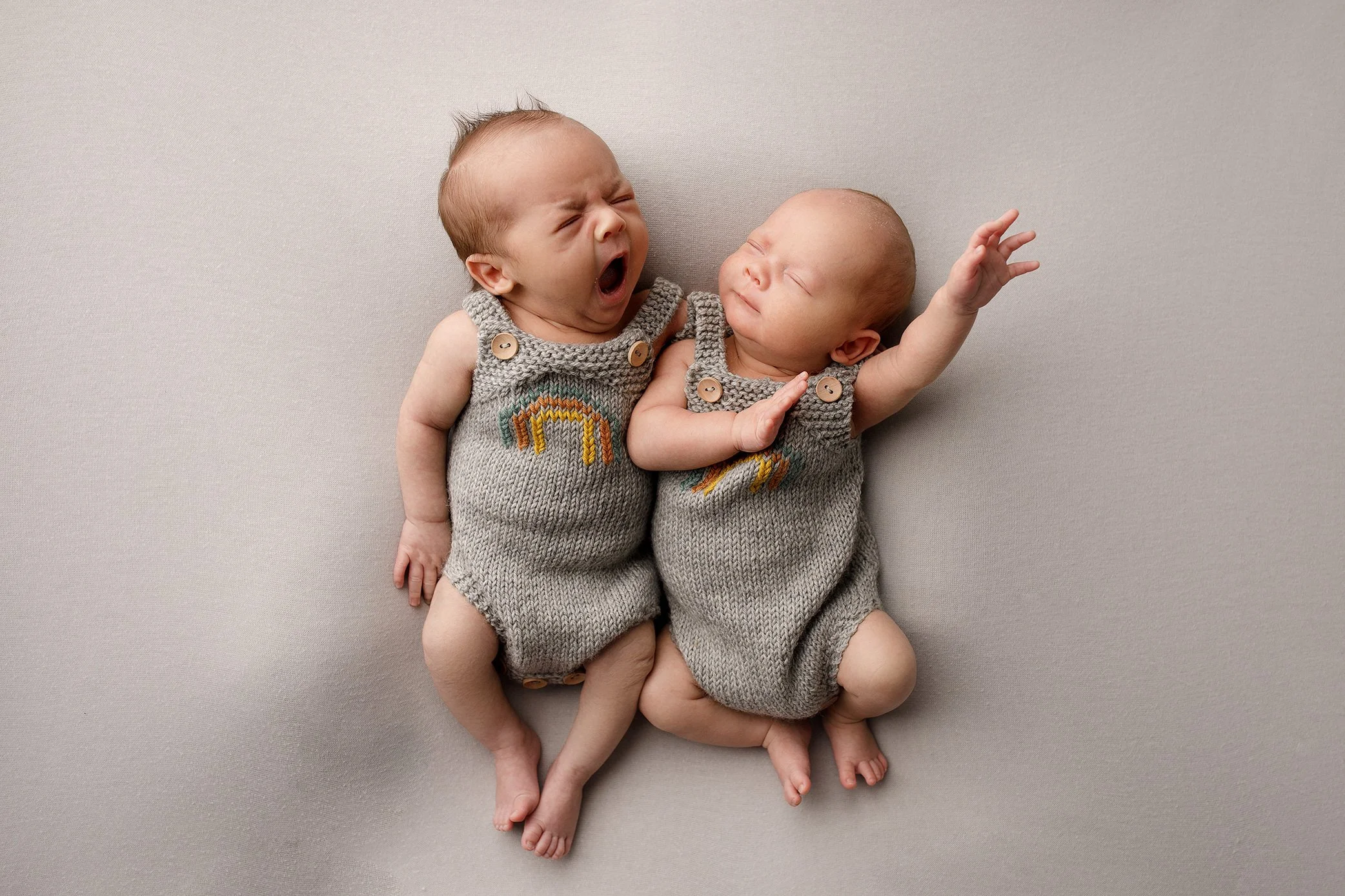 Twin boys wearing grey outfits with rainbow during one month photoshoot in Salem, Oregon