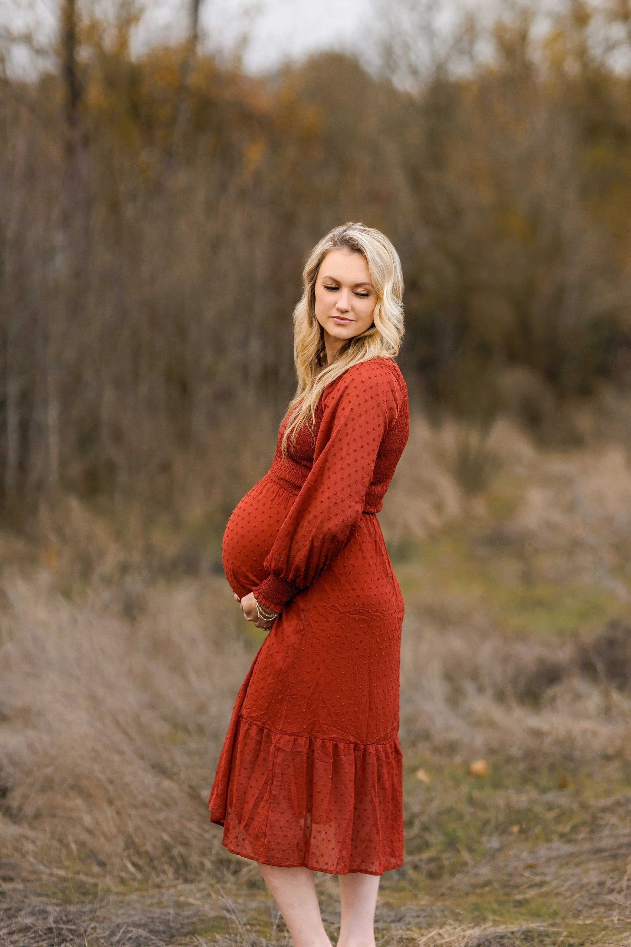 Pregnant mother from Portland Oregon in red dress posing in natural field during outdoor fall maternity session.