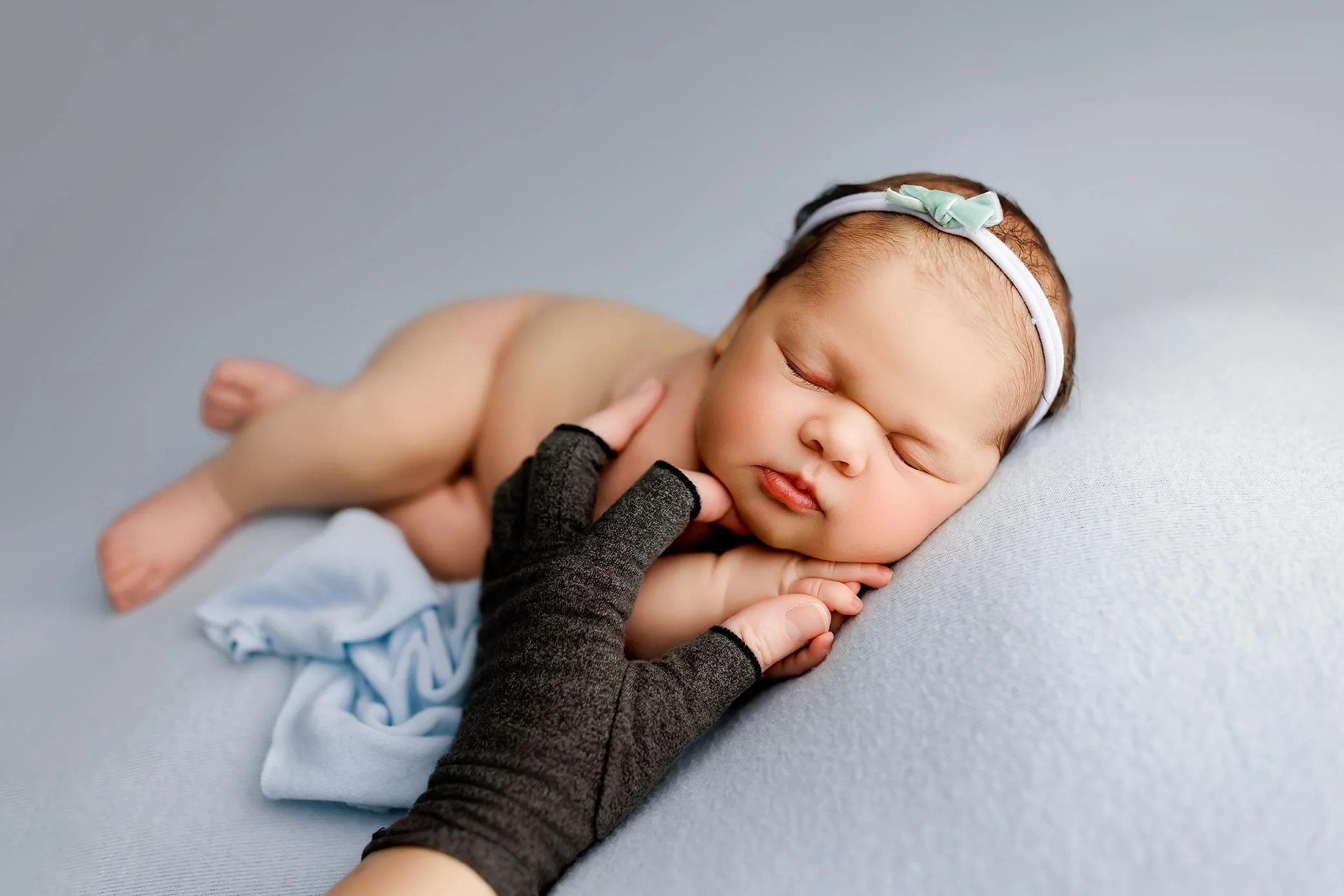 Newborn baby safely posed with photographer hands supporting during studio newborn photography session in Salem Oregon