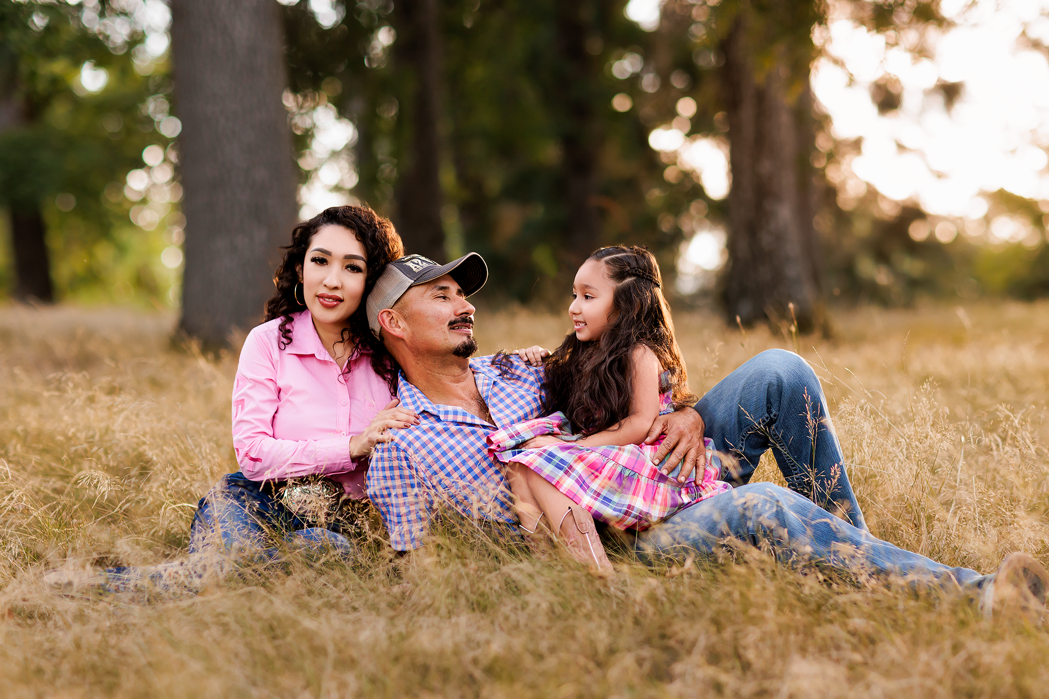 Family reclining together in grassy field during golden hour