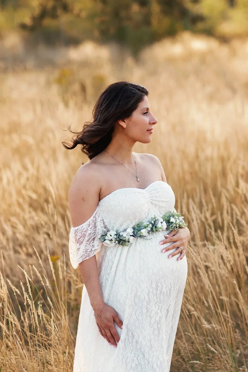 Pregnant mother in white lace dress standing in golden field during maternity session in Salem Oregon