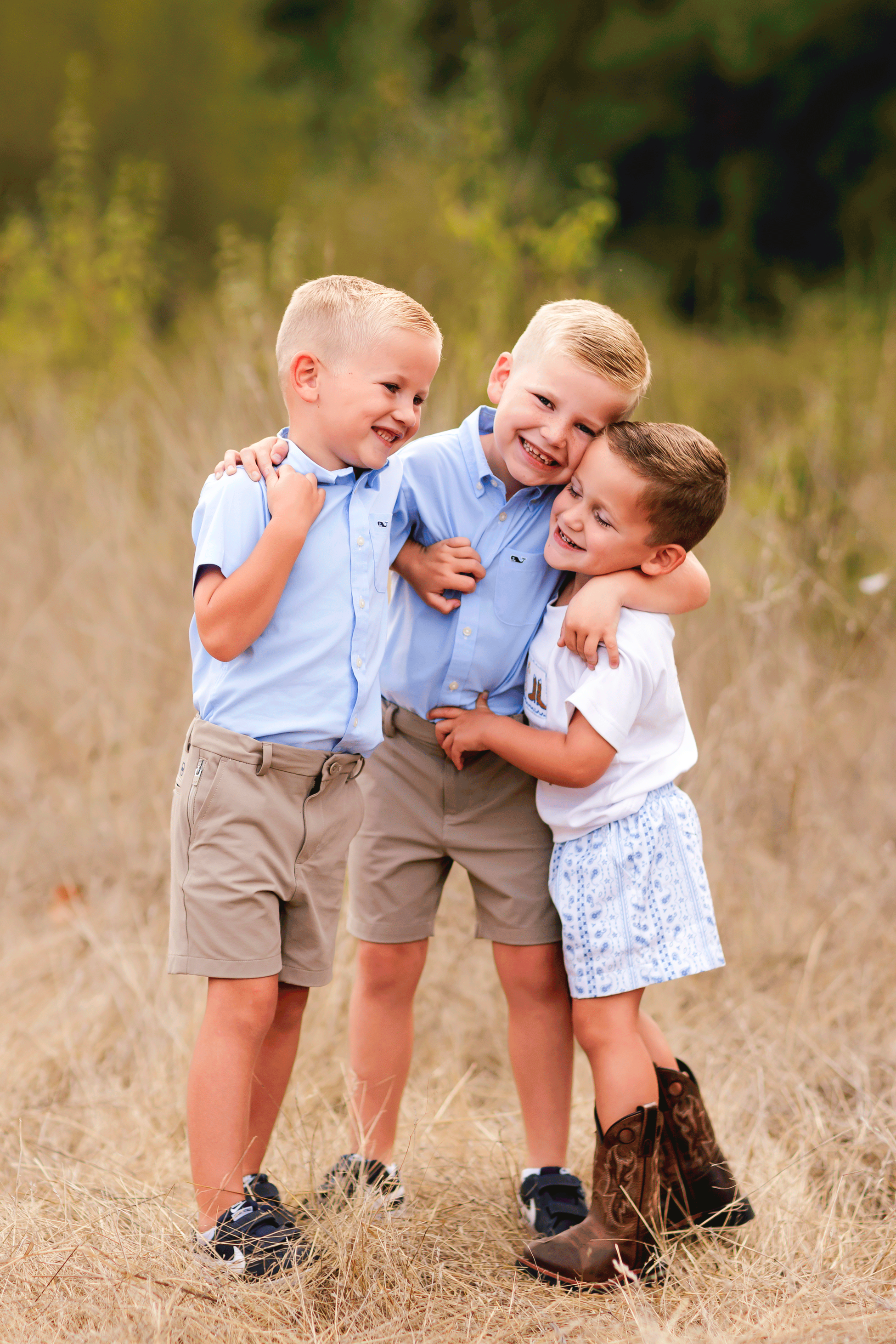Three young brothers hugging and laughing together during an outdoor family photography session