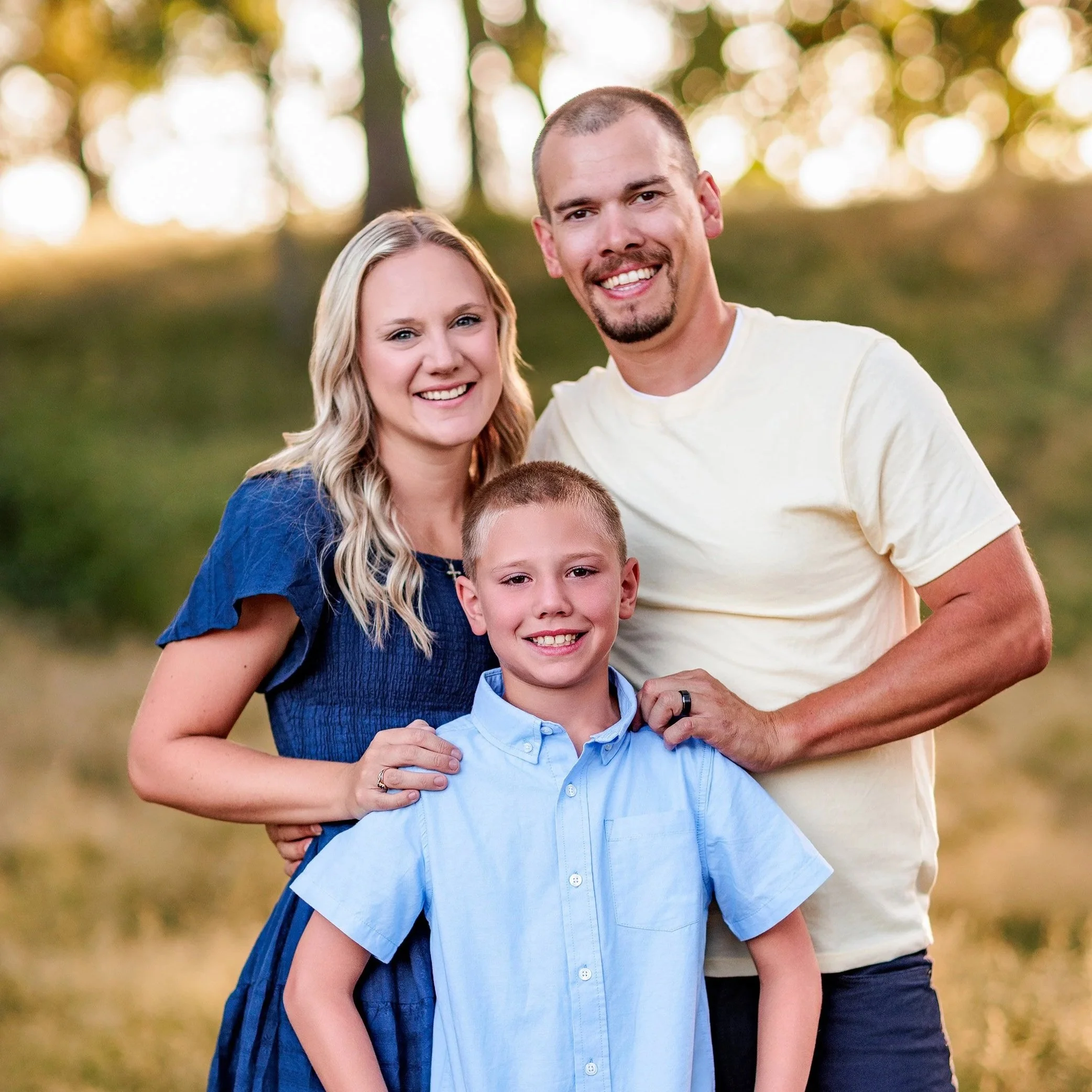 Parents standing behind older son during golden hour outdoor family photography session.