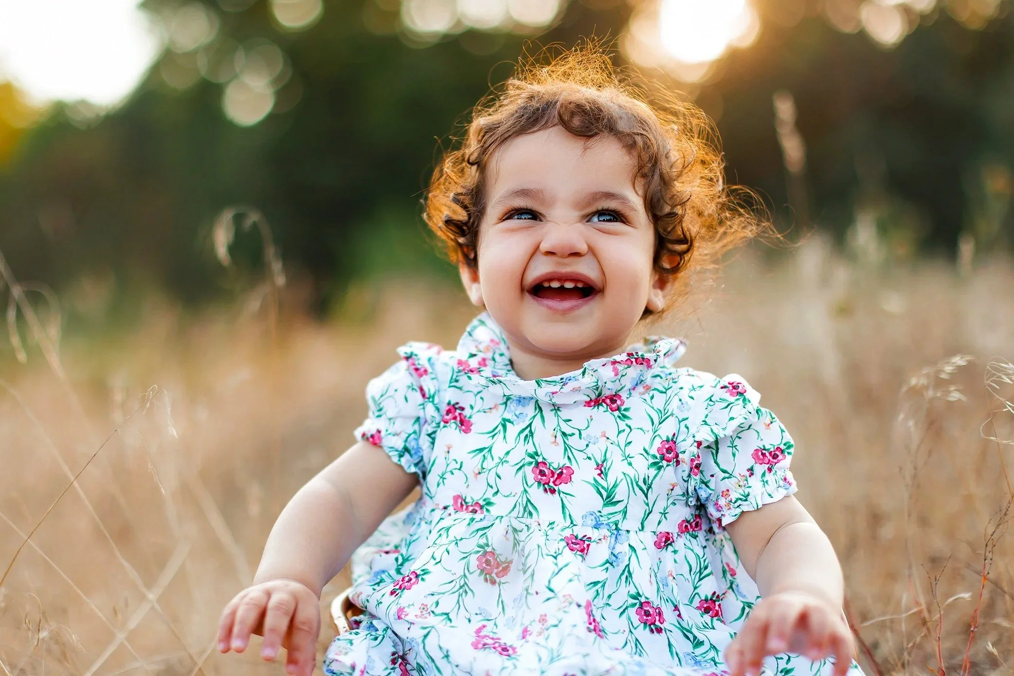 Smiling baby with curly hair during golden hour outdoor portrait session in Salem Oregon