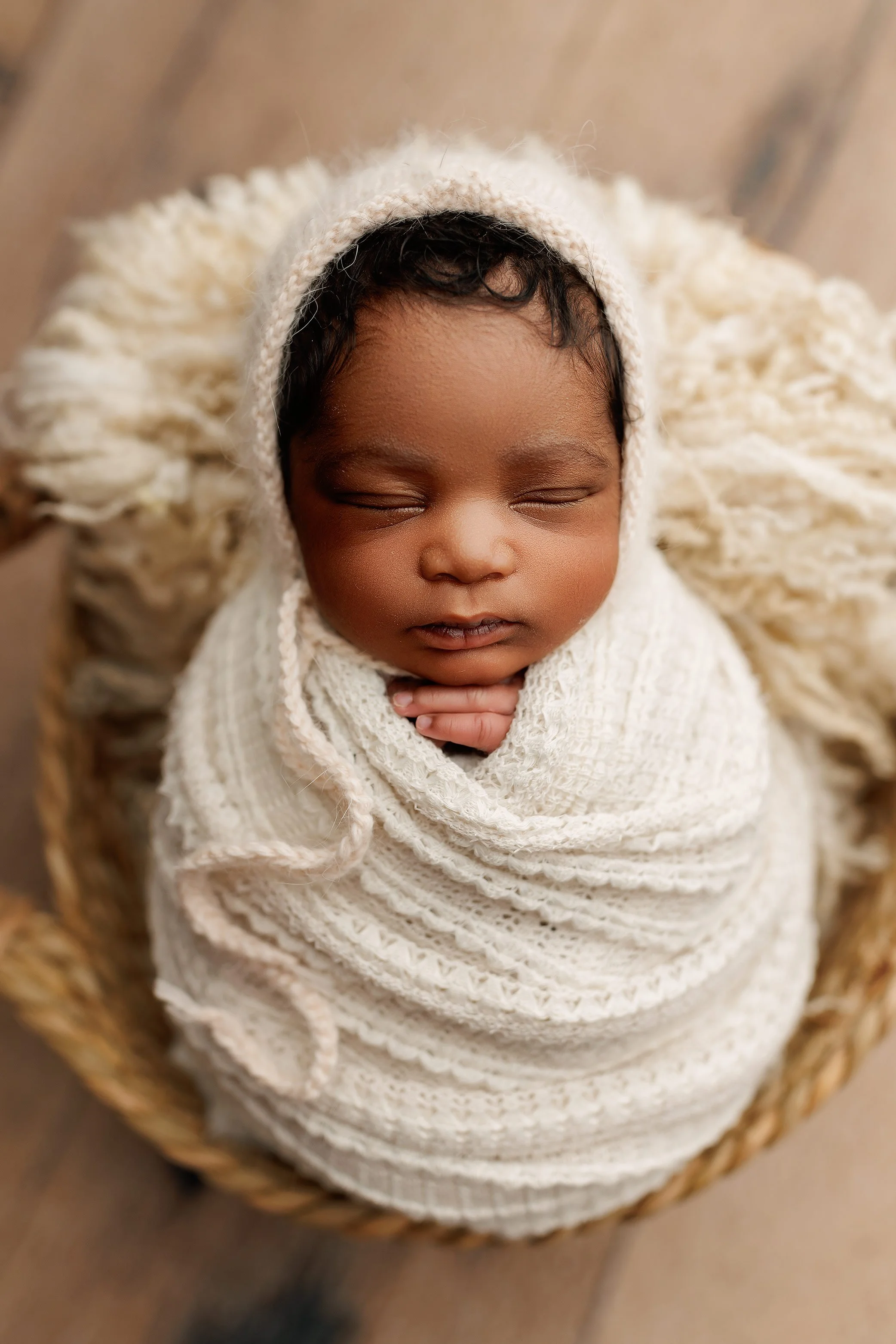 Close-up newborn portrait of a sleeping baby wrapped in a soft textured blanket