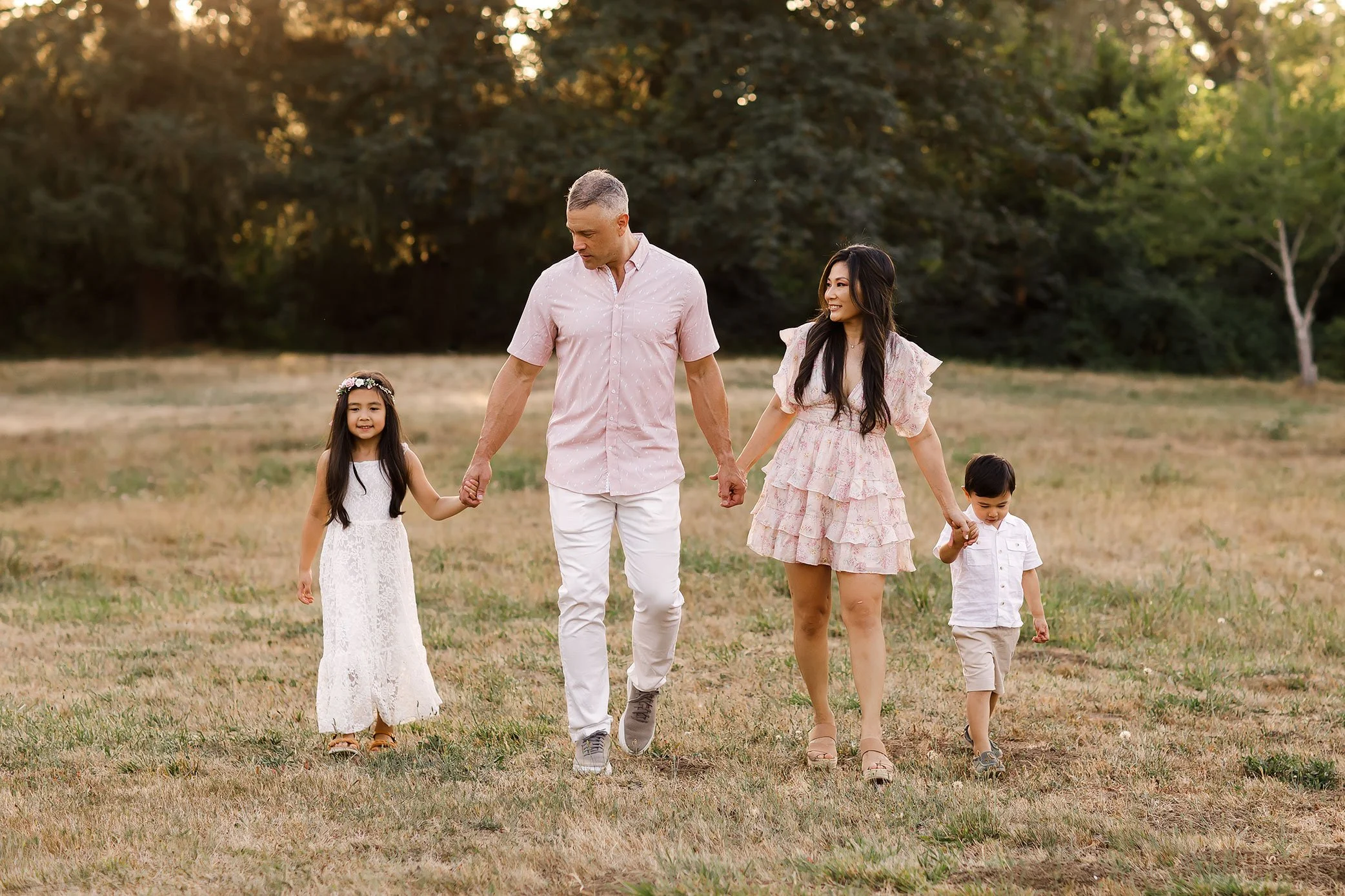 Family of four walking hand in hand across open field