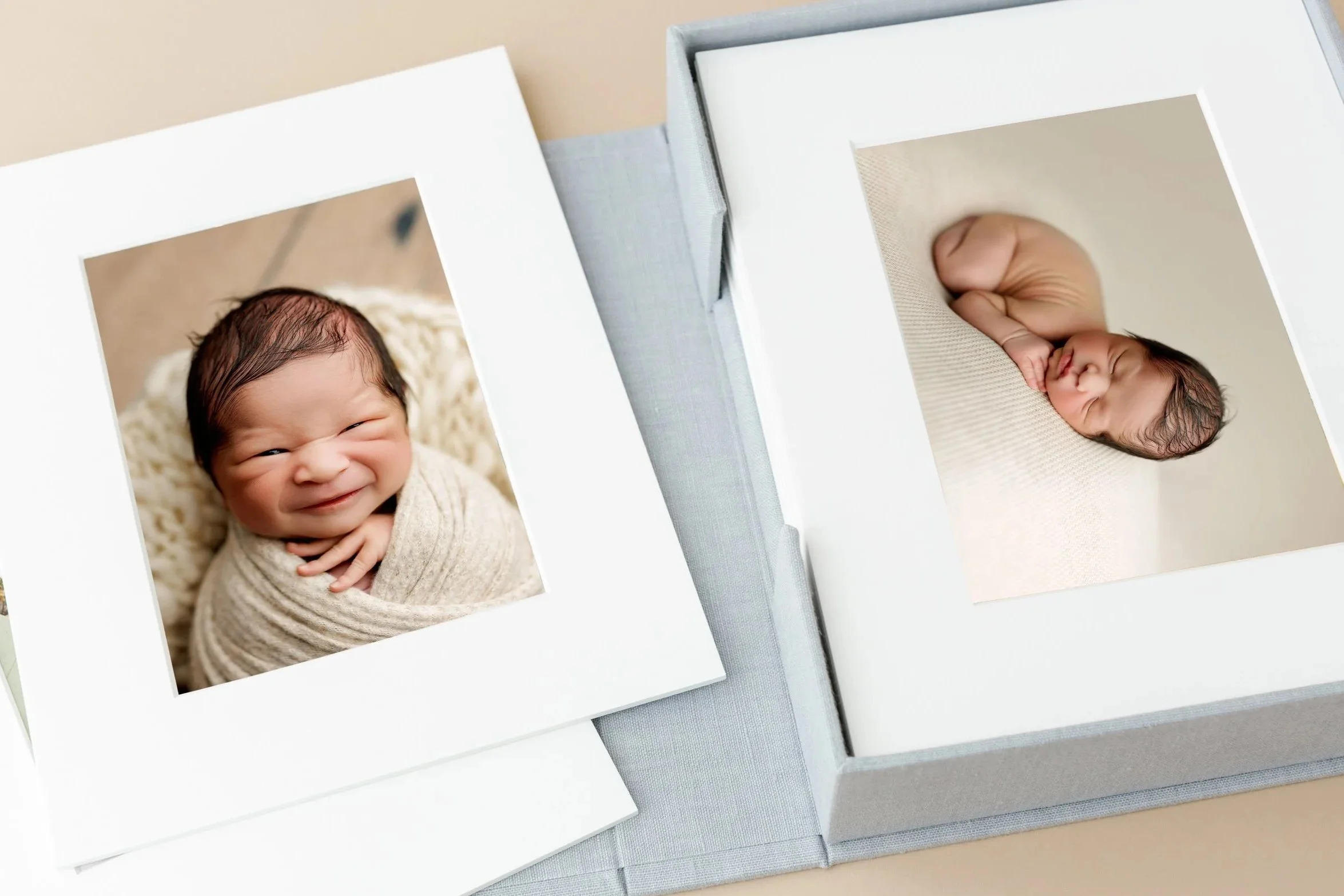 Handcrafted keepsake box filled with matted newborn prints, showing two sweet portraits displayed in a linen box.