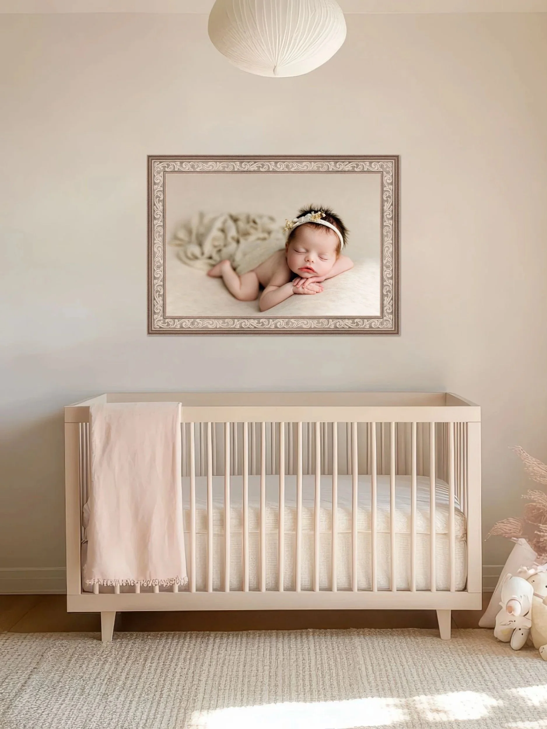 Framed newborn portrait displayed above crib in soft neutral nursery, highlighting heirloom wall art for baby’s room