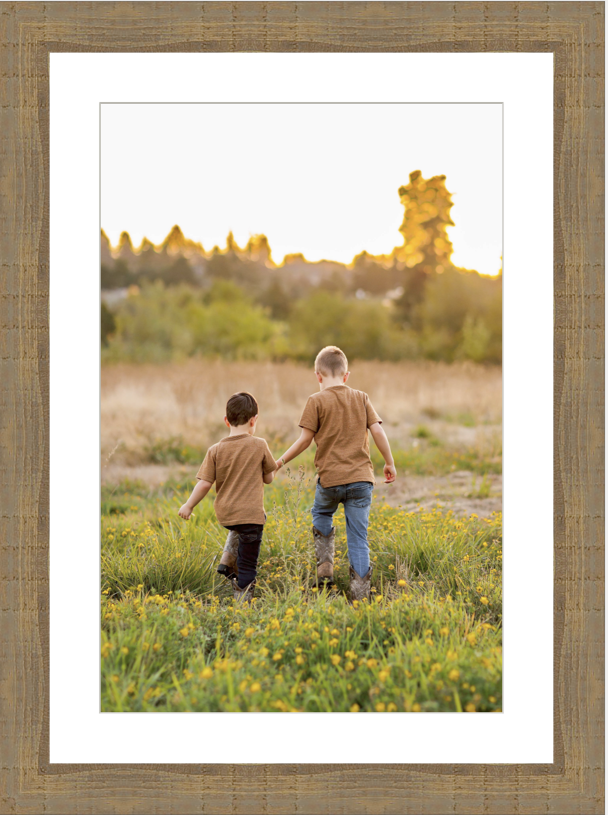 Two young boys walking through a golden field at sunset, framed as wall art print