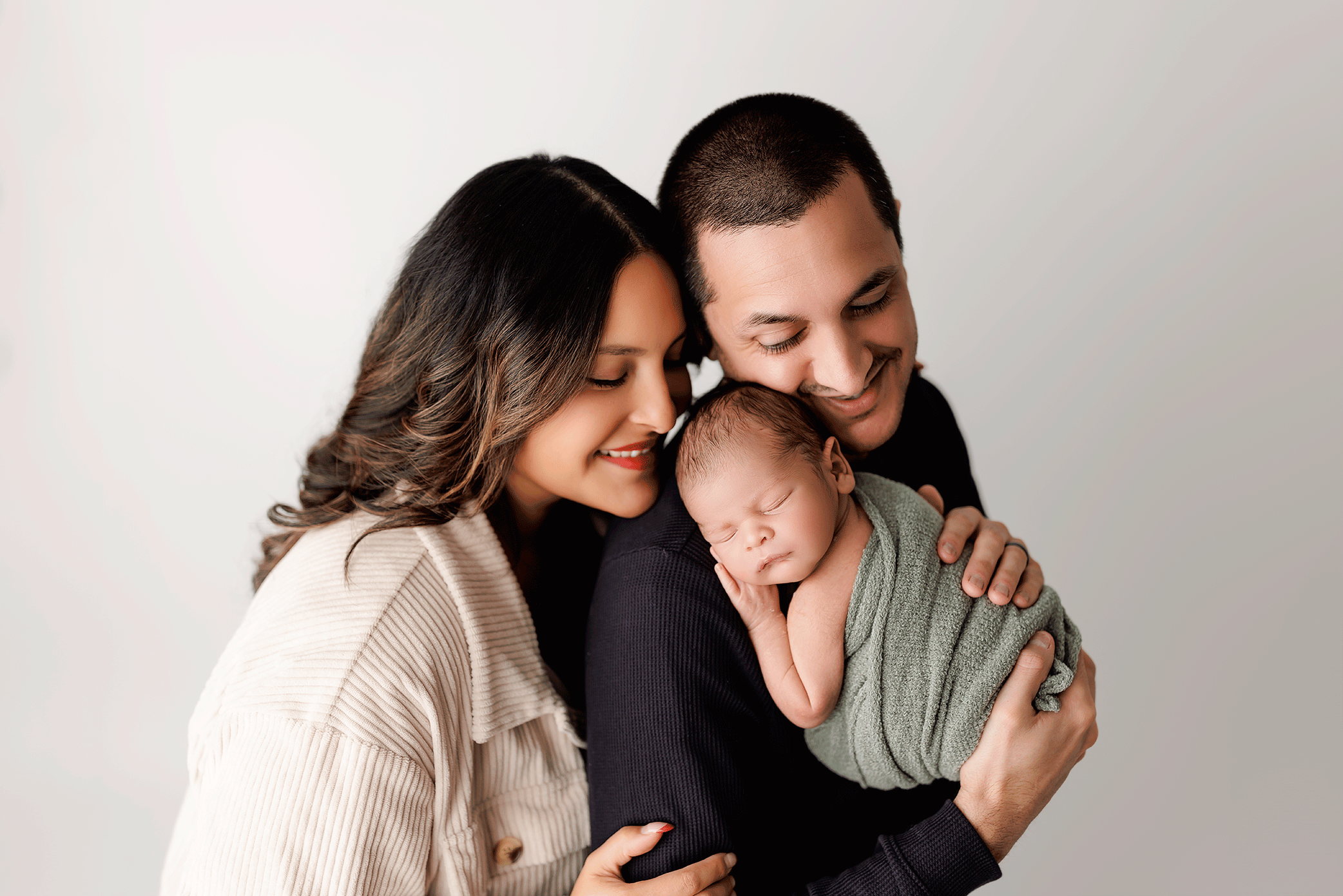 Parents holding their sleeping newborn during a professional newborn photography session.