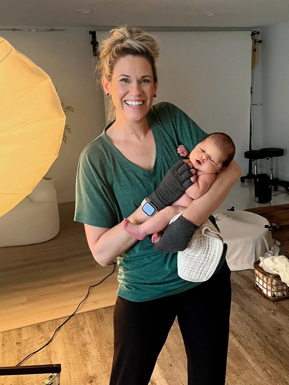 Professional newborn photographer in Salem Oregon holding and safely supporting a newborn baby during studio session