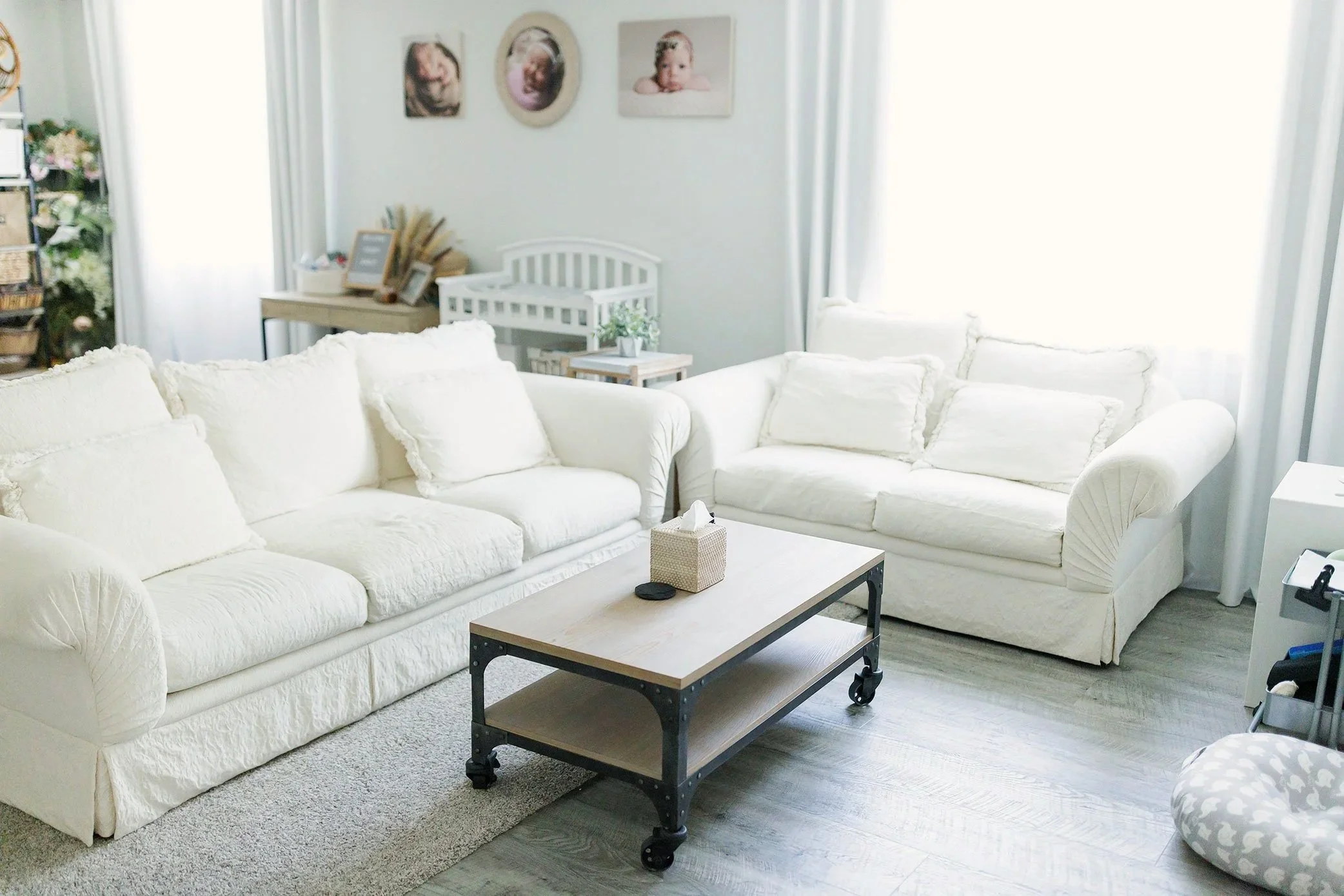 Bright and cozy newborn photography studio with seating and crib in background