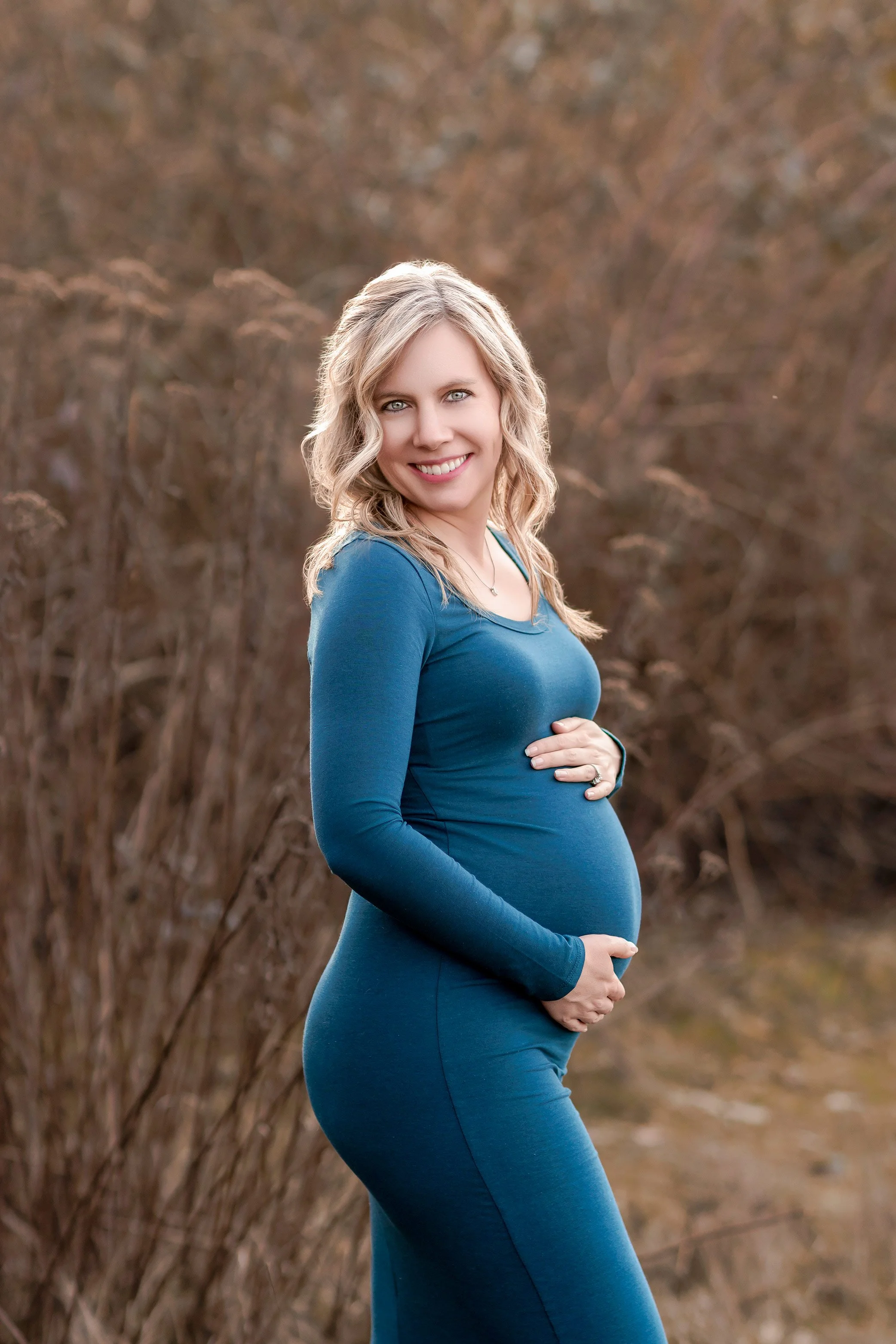 Expecting mother in teal dress posing in natural field during maternity photography session in Salem Oregon
