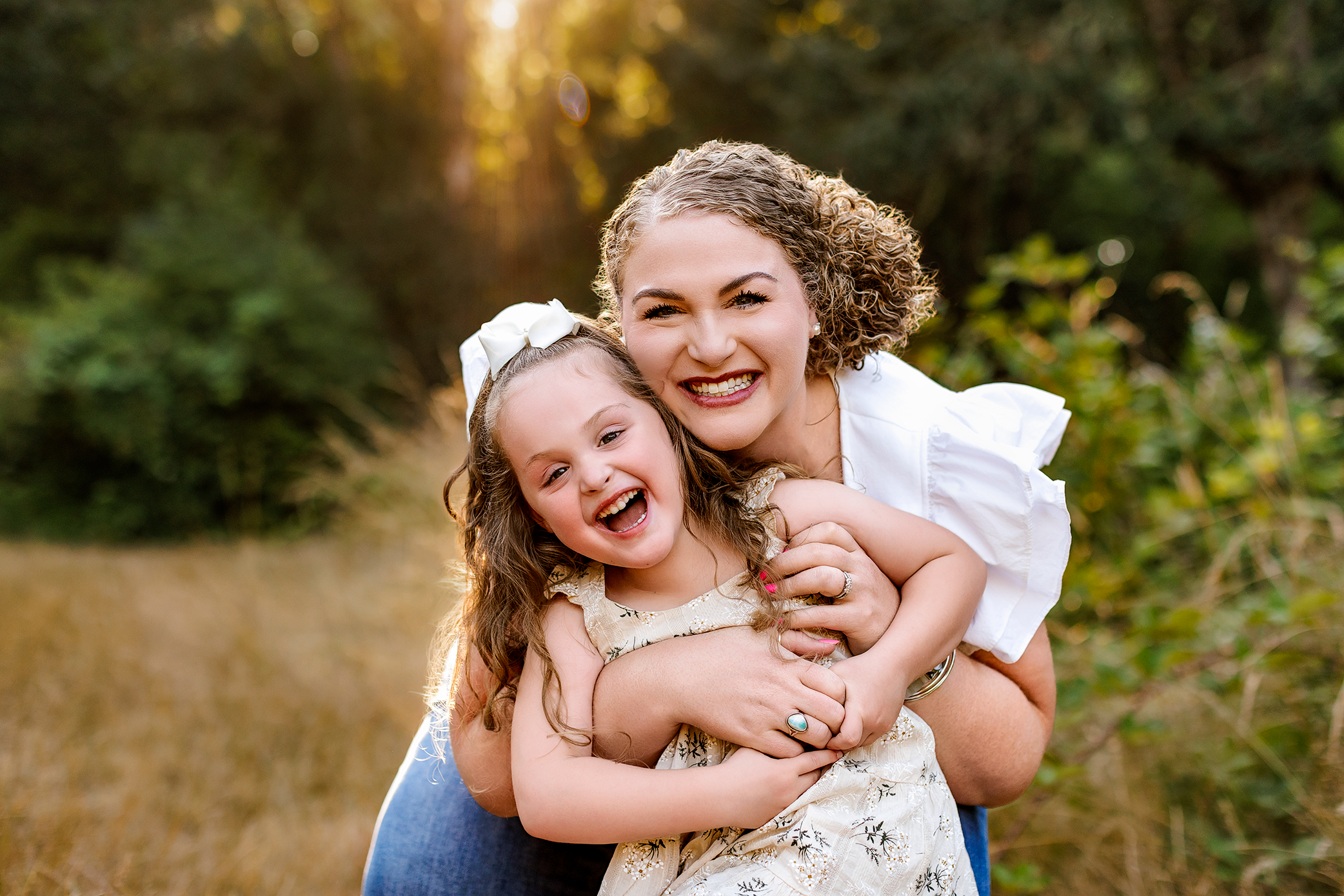 Mother hugging and laughing with her daughter in warm sunset light during a Salem, Oregon family session.